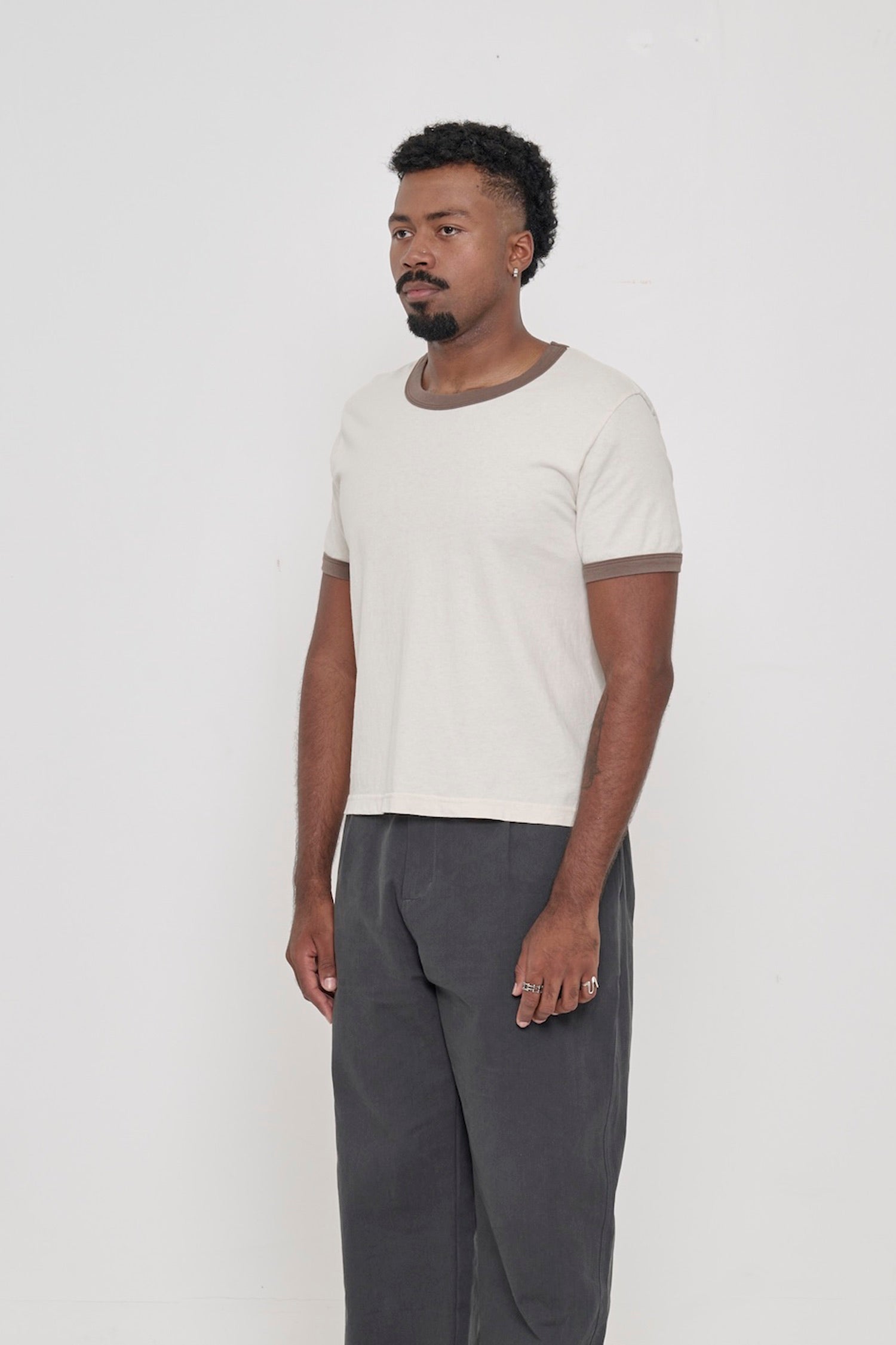 A person turned 45-degrees from the front, wearing a Dry Soil Ringer Trash Tee, showing the side seams and slim fit.