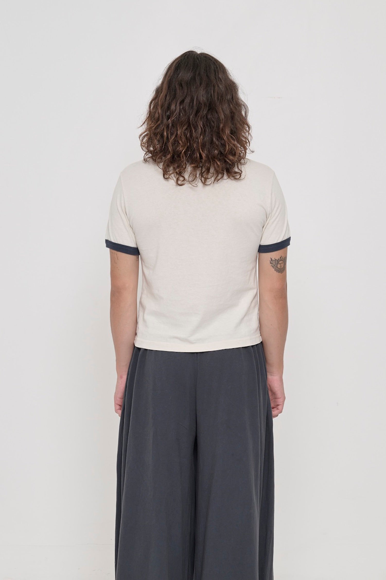 Slate Ringer Trash Tee, back view on a person. Sized up for a relaxed slim fit.