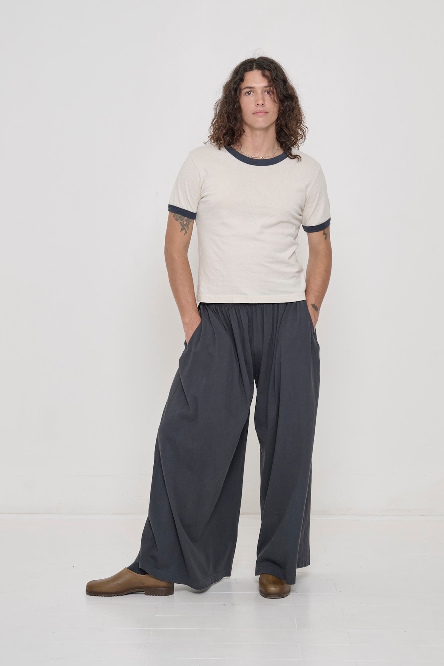 A person wearing a Slate Ringer Trash Tee with Tubular Pants in Slate.