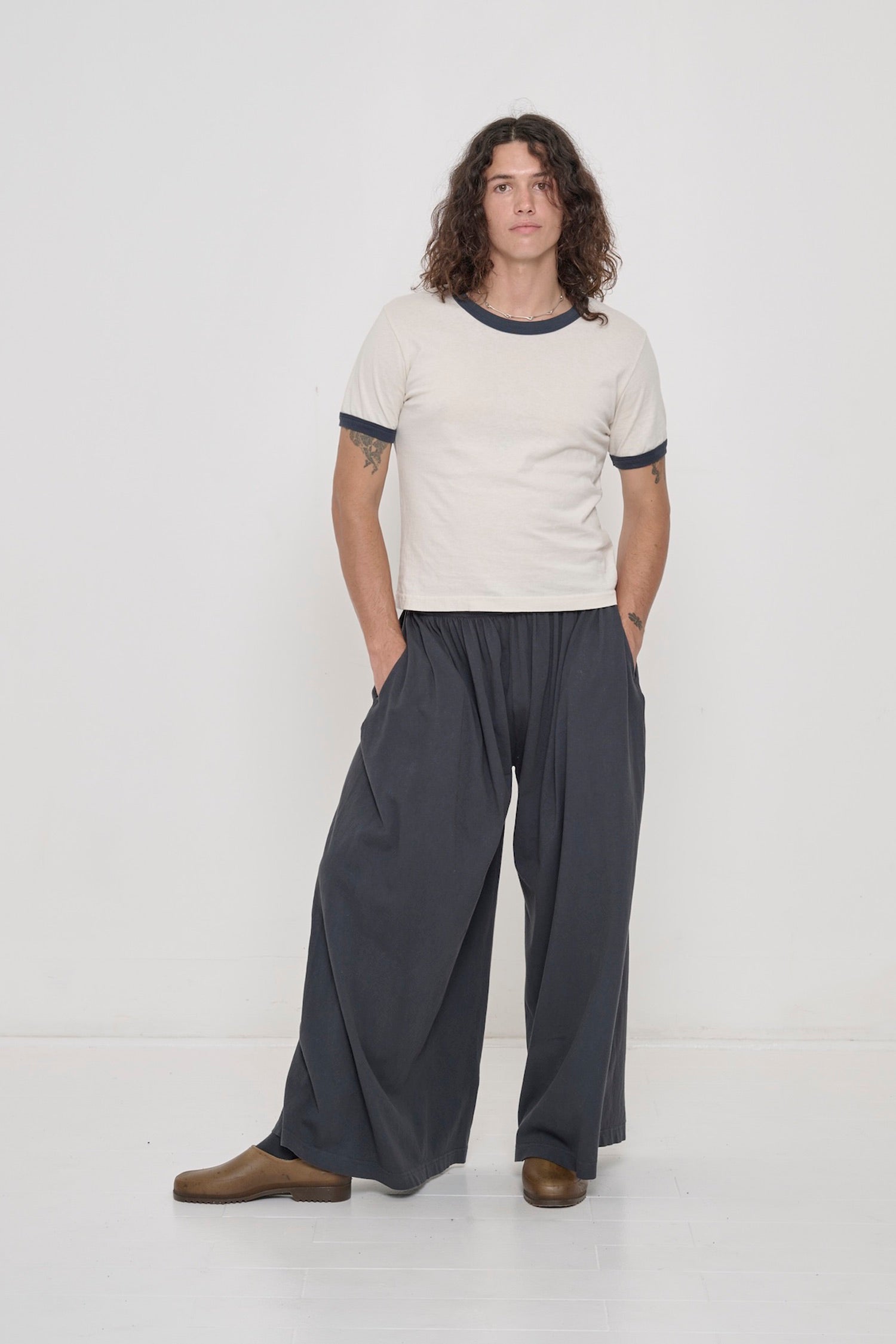 A person wearing a Slate Ringer Trash Tee with Tubular Pants in Slate.