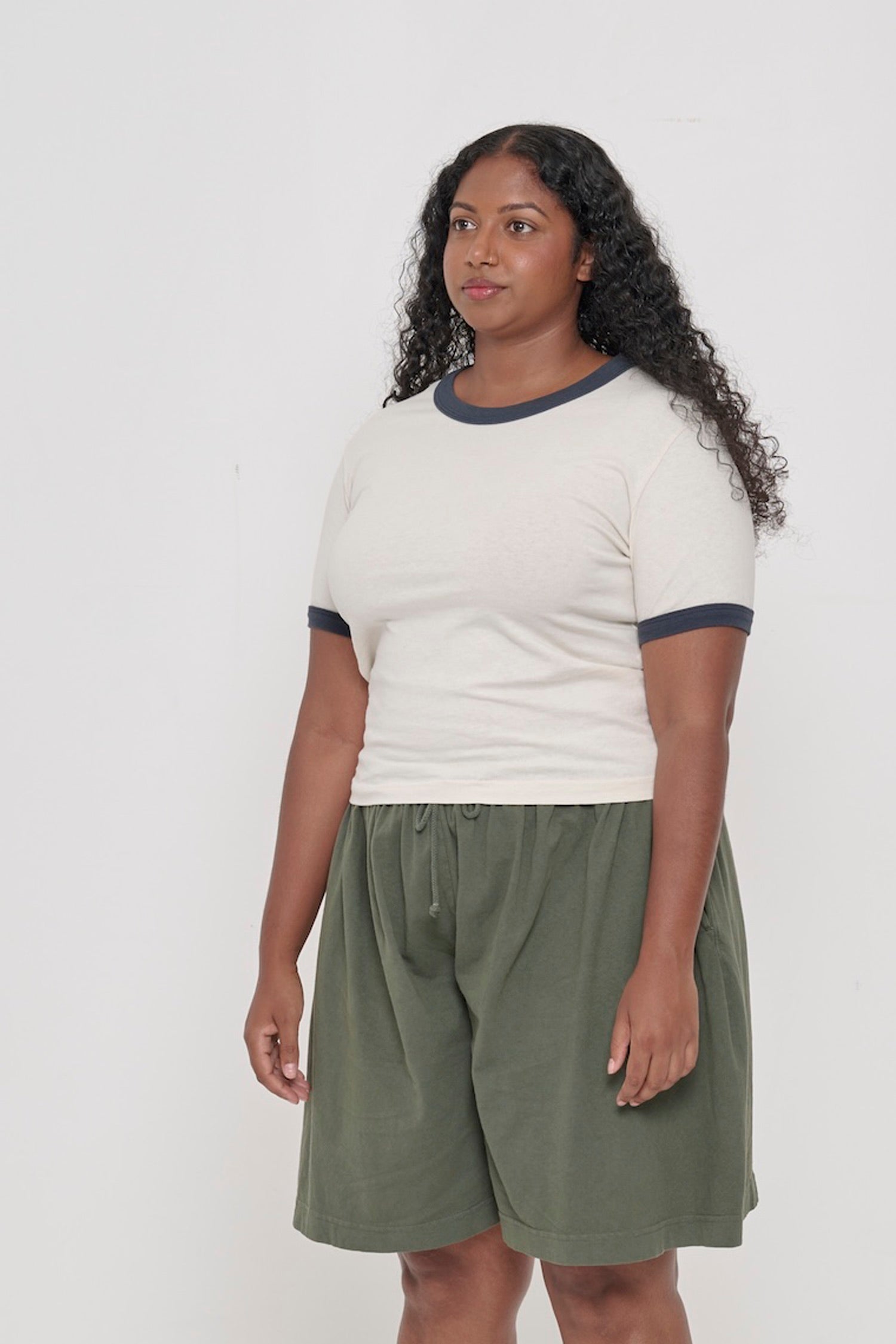 A person turned 45-degrees from the front, wearing a Slate Ringer Trash Tee, showing the side seams and slim fit.