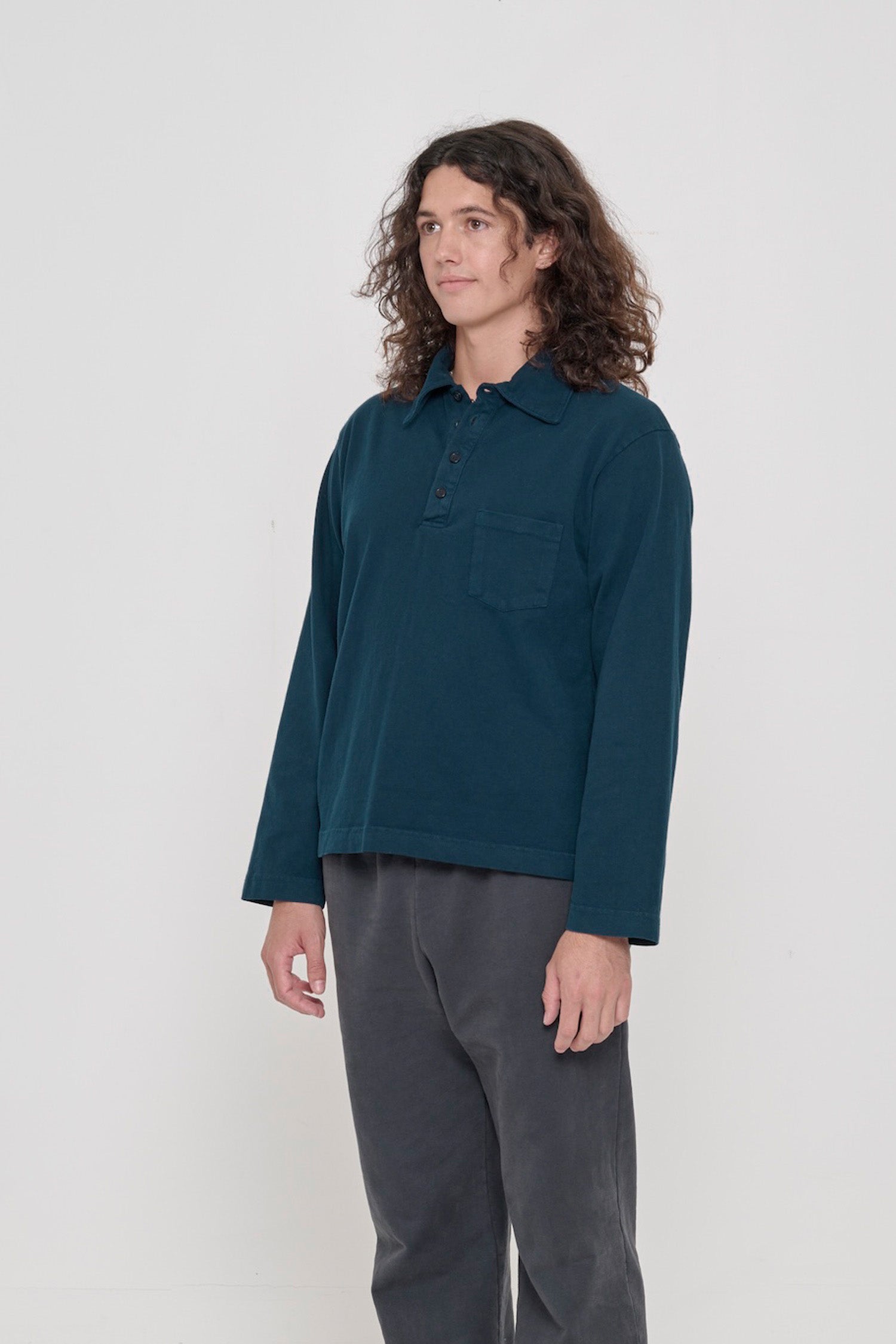 Person turned 45 degrees, wearing a Juniper Rugby Trash Polo, showing relaxed sleeves.