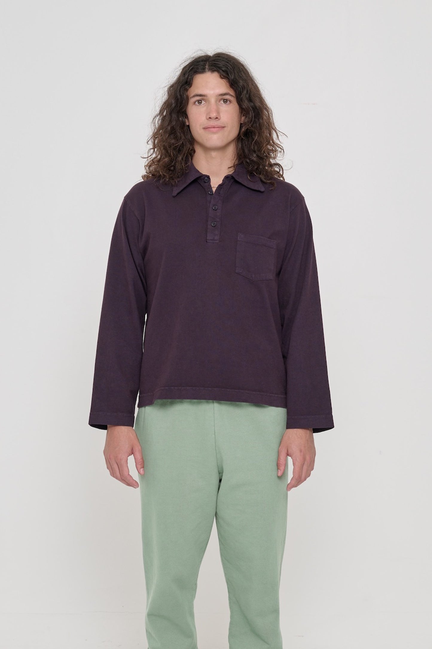 Front view of a 6' person wearing a size M Rugby Trash Polo in Mulberry. Hem hits lower-mid hip.
