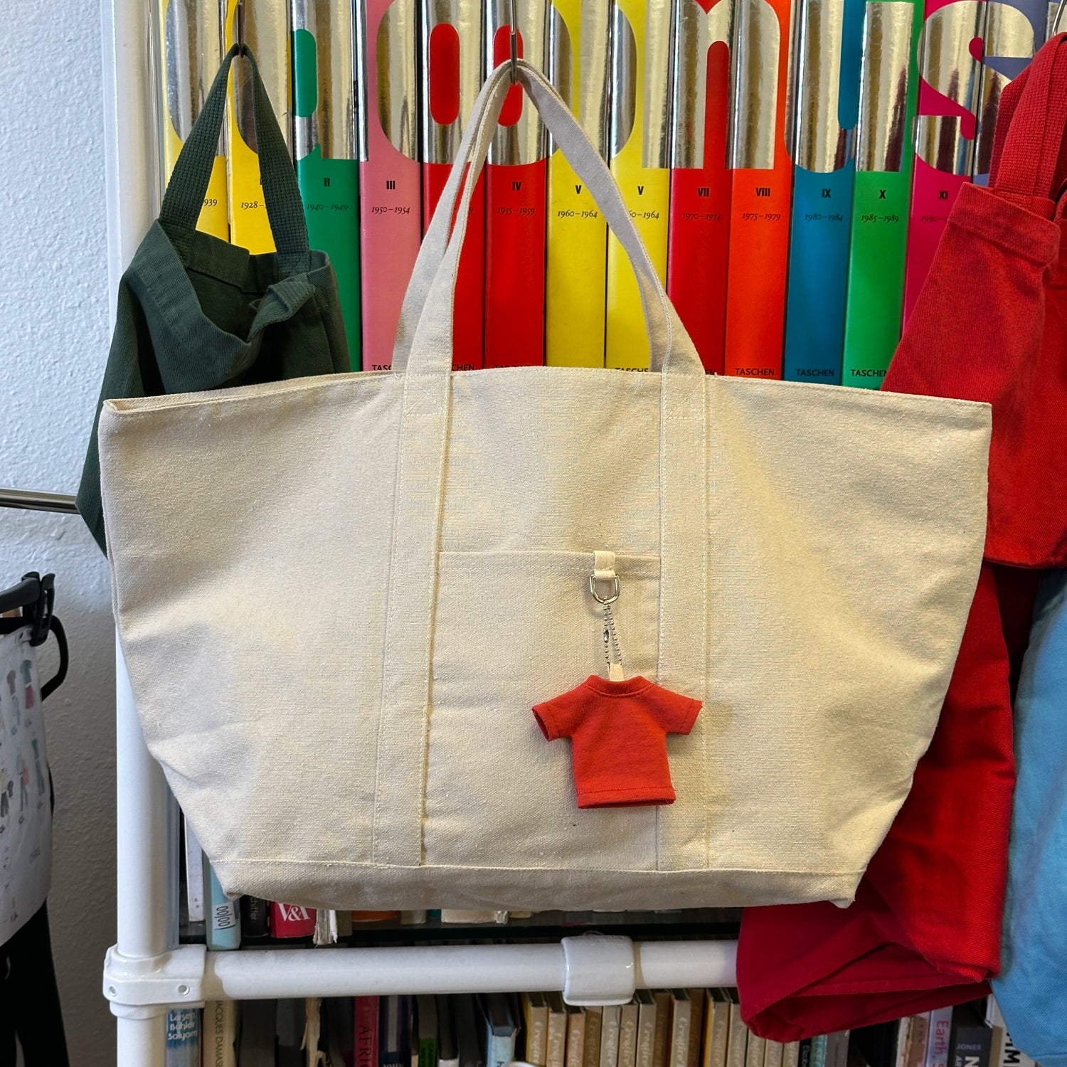 A beige canvas Boat Tote with a small red Trash Tee keychain.