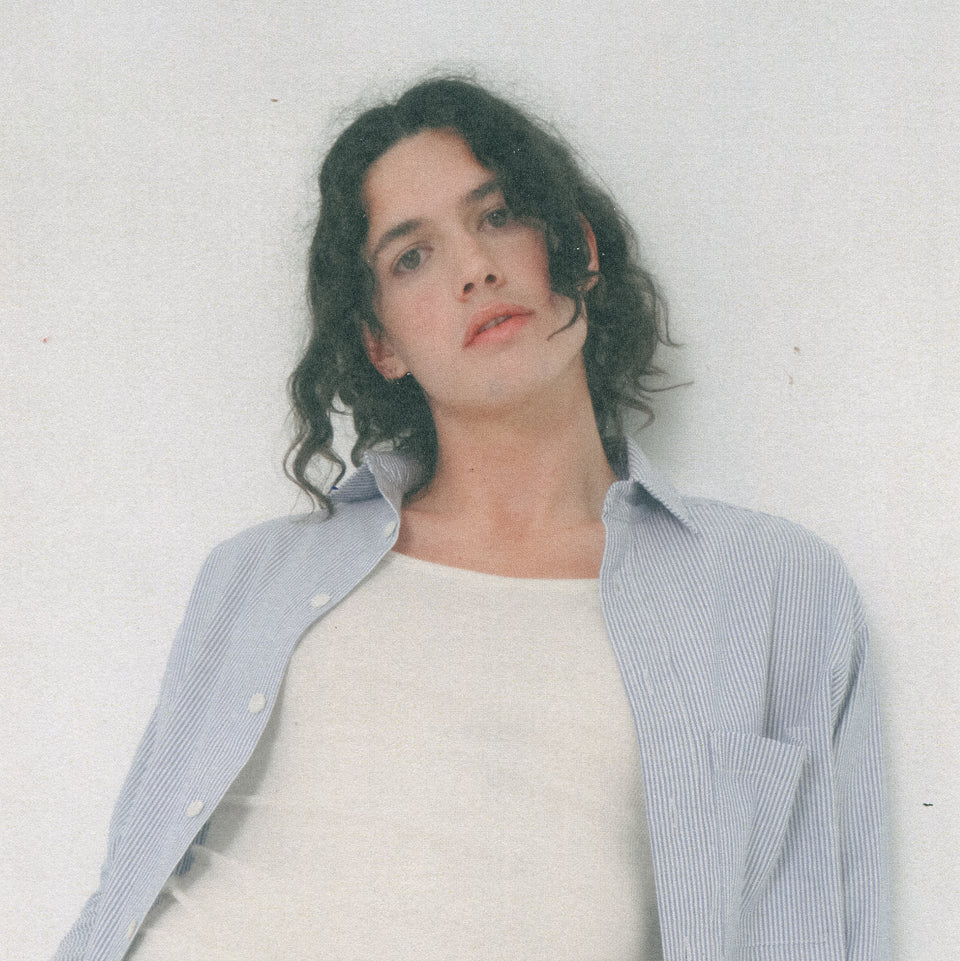 Person wearing a blue and white Poplin Stripe Button-Up shirt over a Rib Tank in White against a plain background.