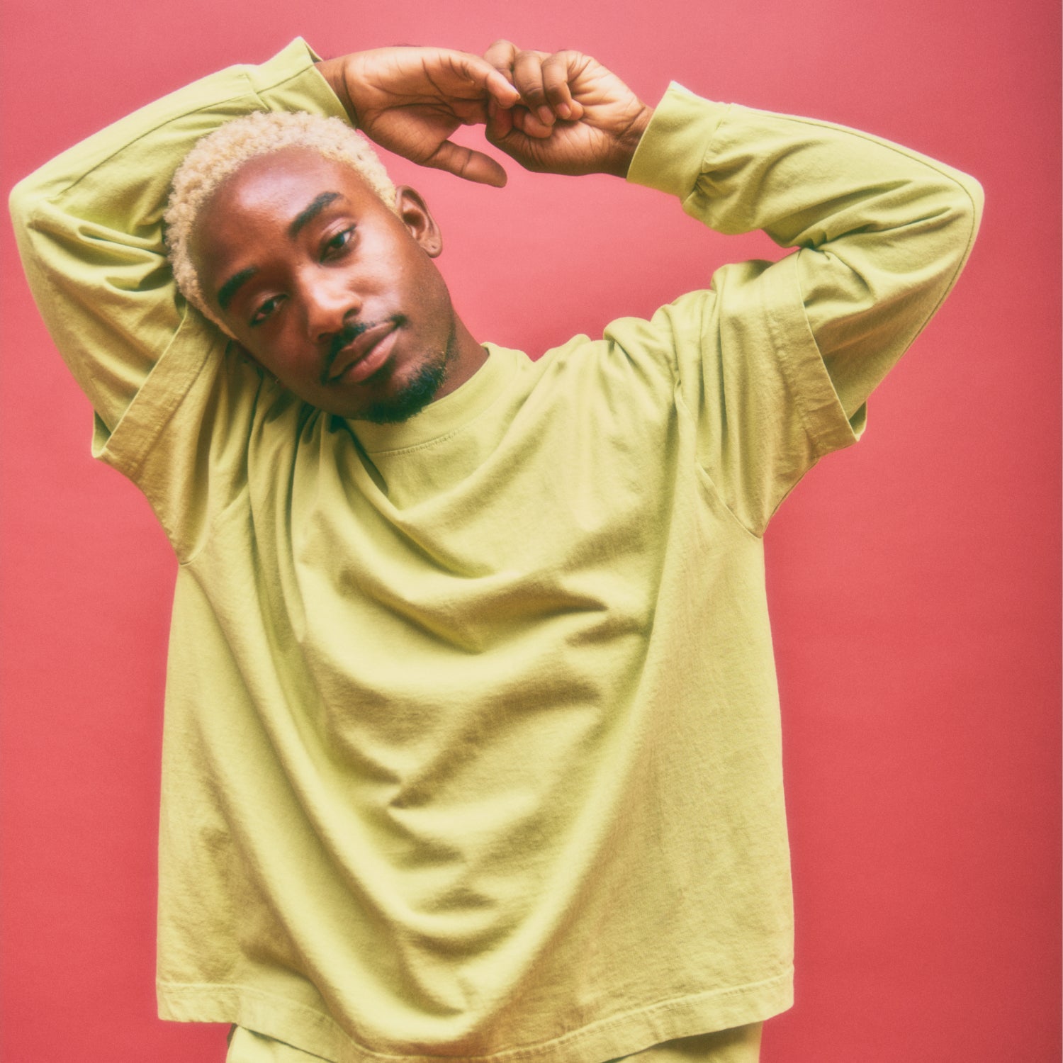 Model standing with arms held above their head, wearing a Long Sleeve Trash Tee layered beneath a Short Sleeve Trash Tee, both in Cardamom