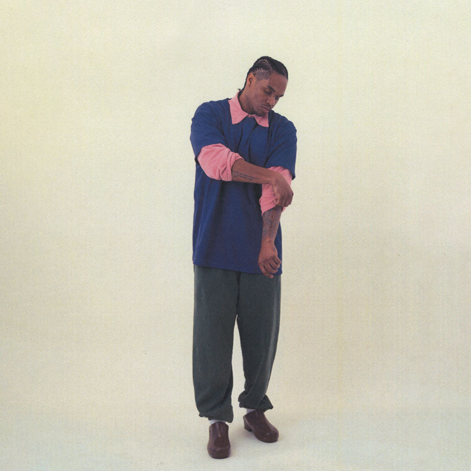 Model standing and pulling up sleeve, wearing a Short Sleeve Trash Tee in Washed Navy layered over Trash Ruby Polo in Wild Rose, and Trash Sweatpants in Slate.