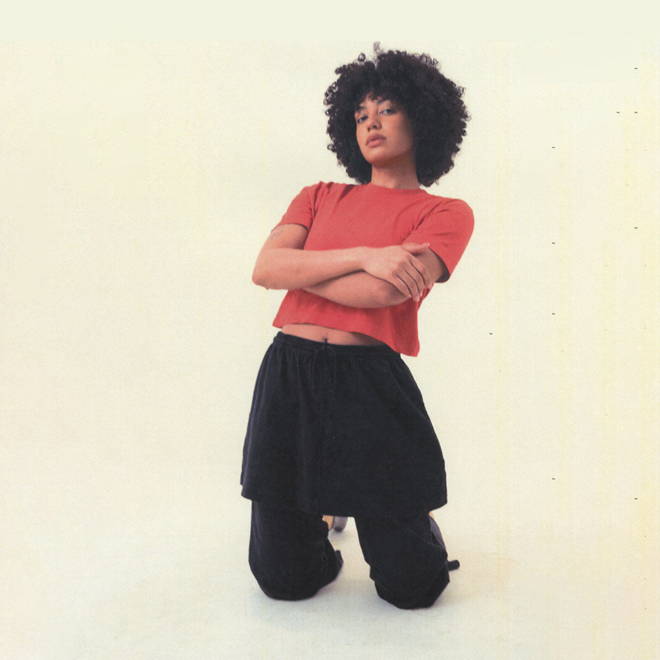 Person wearing a Cedar Baby Trash Tee and Black Apartment Pants, knelling on the ground against a plain background