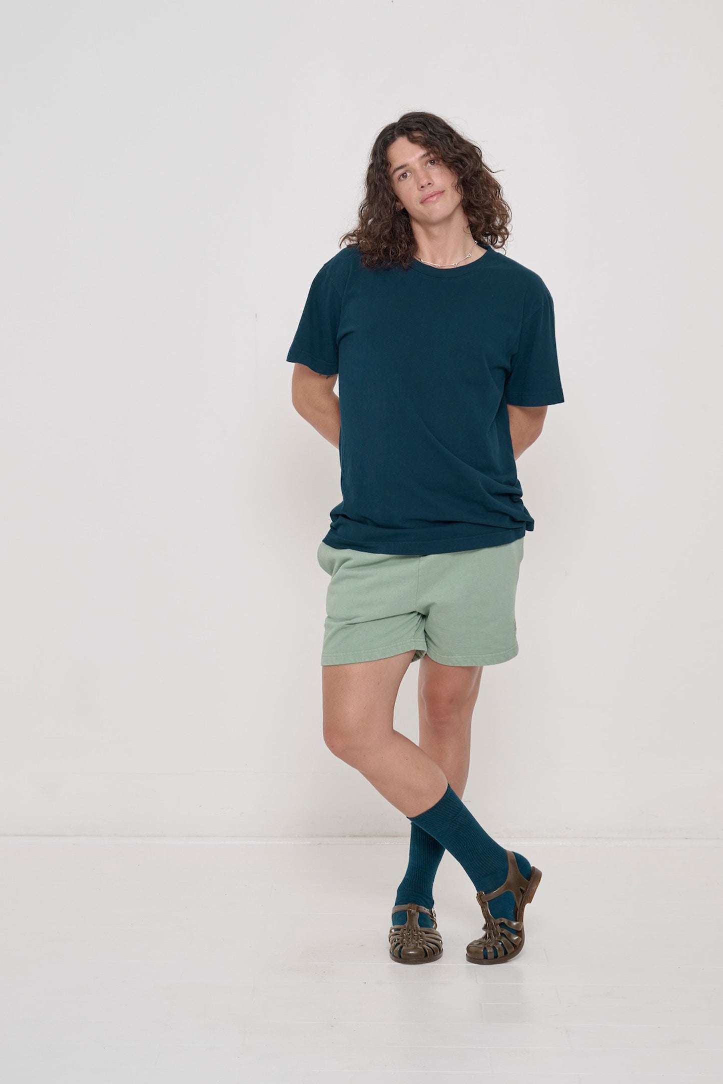 Front view of a person wearing the Short Sleeve Trash Tee in Juniper, with a pair of Trash Fleece Everyday Shorts.