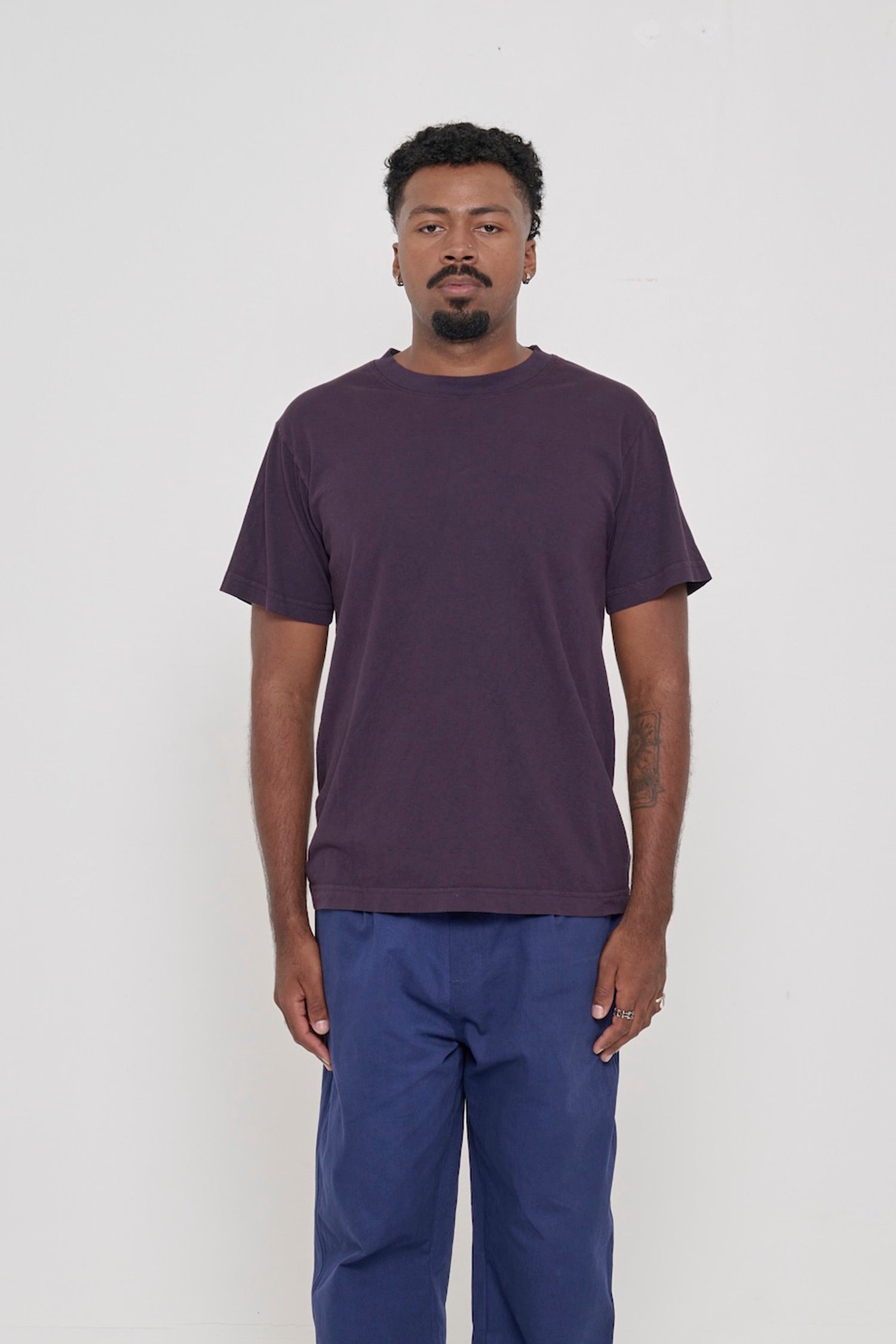 Front view of a person wearing the Short Sleeve Trash Tee in Mulberry, showcasing its relaxed fit, hem hits below the hip.