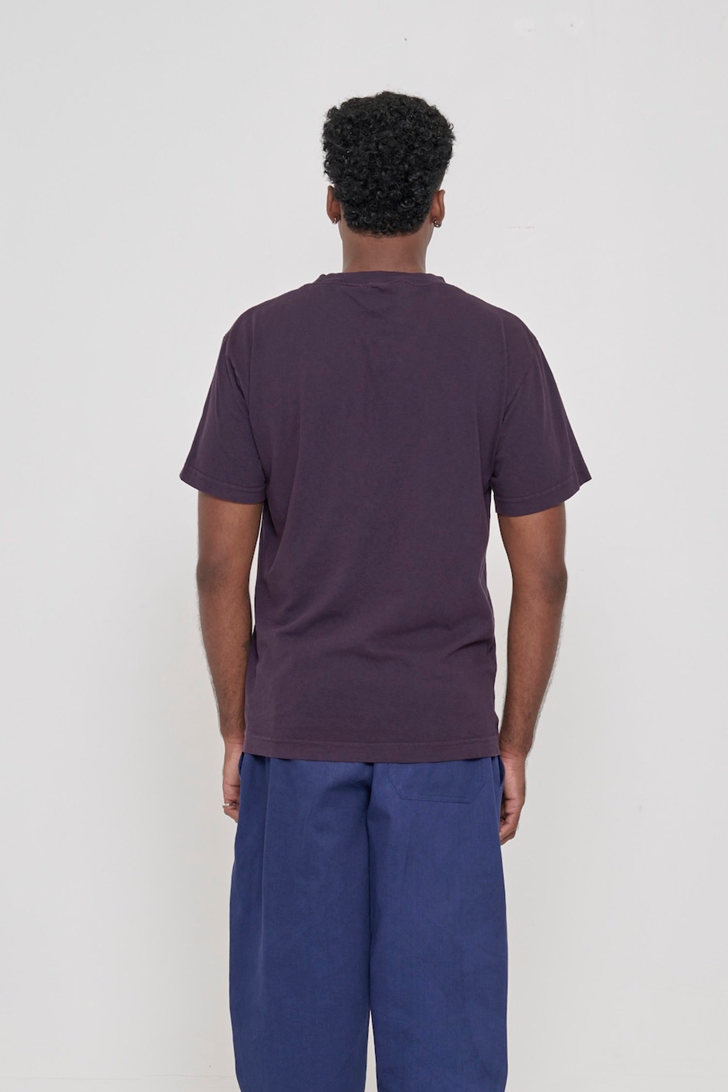 Back view of a person wearing the Short Sleeve Trash Tee in Mulberry, showing the relaxed slim body and wide sleeve.