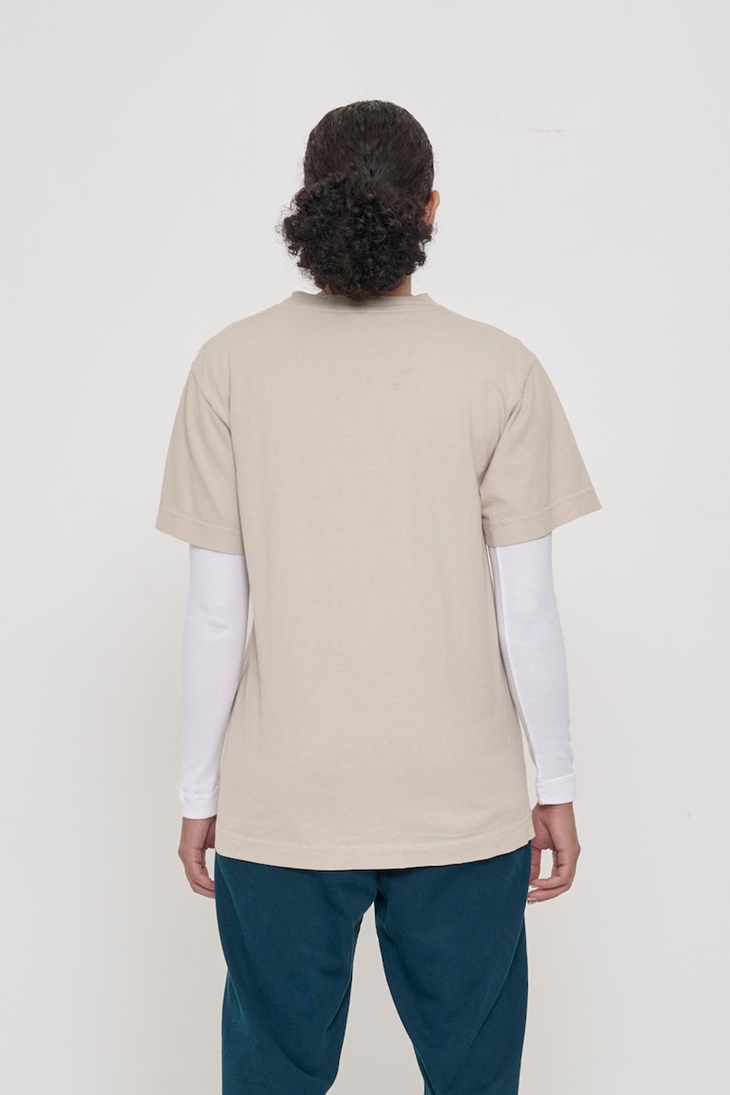 Back view of a woman wearing the Short Sleeve Trash Tee in Oat, showing the relaxed slim body and wide sleeve.