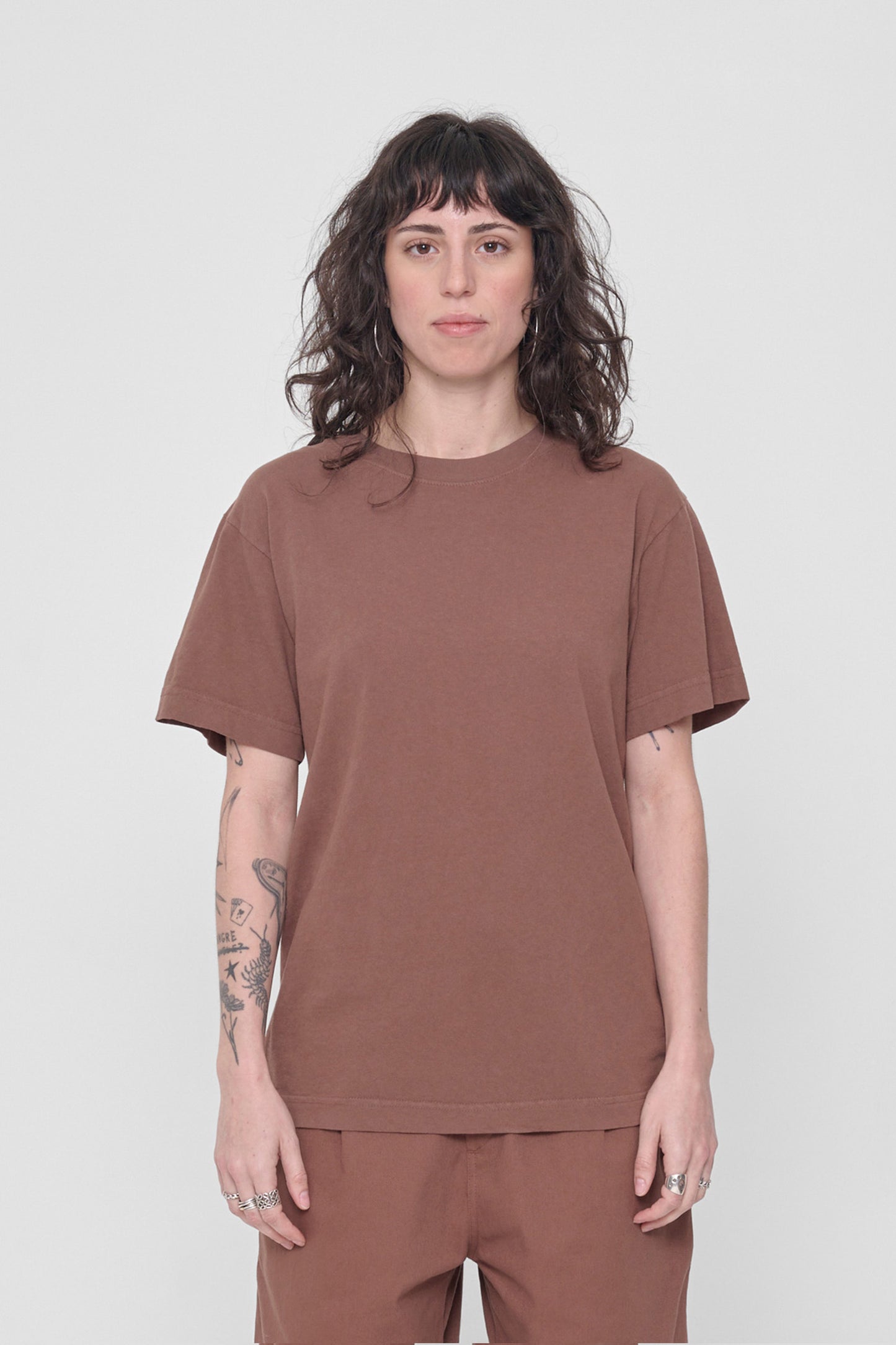 A 5'6" woman in a size S Potting Soil brown Short Sleeve Trash Tee. Hem at her lower hip.