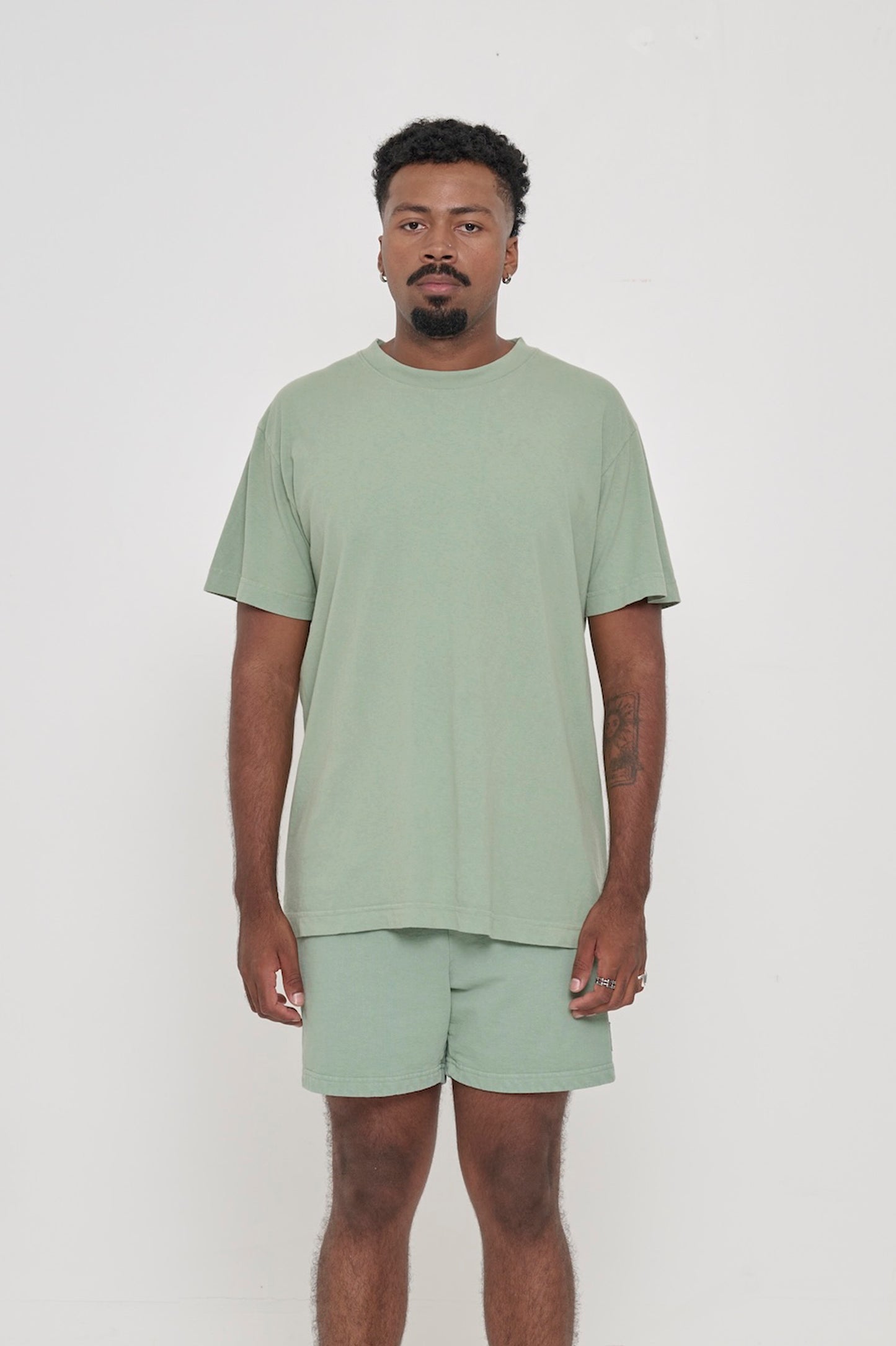 Front view of a man wearing the Short Sleeve Trash Tee in Wasabi, showcasing its relaxed fit, hem hits below the hip.