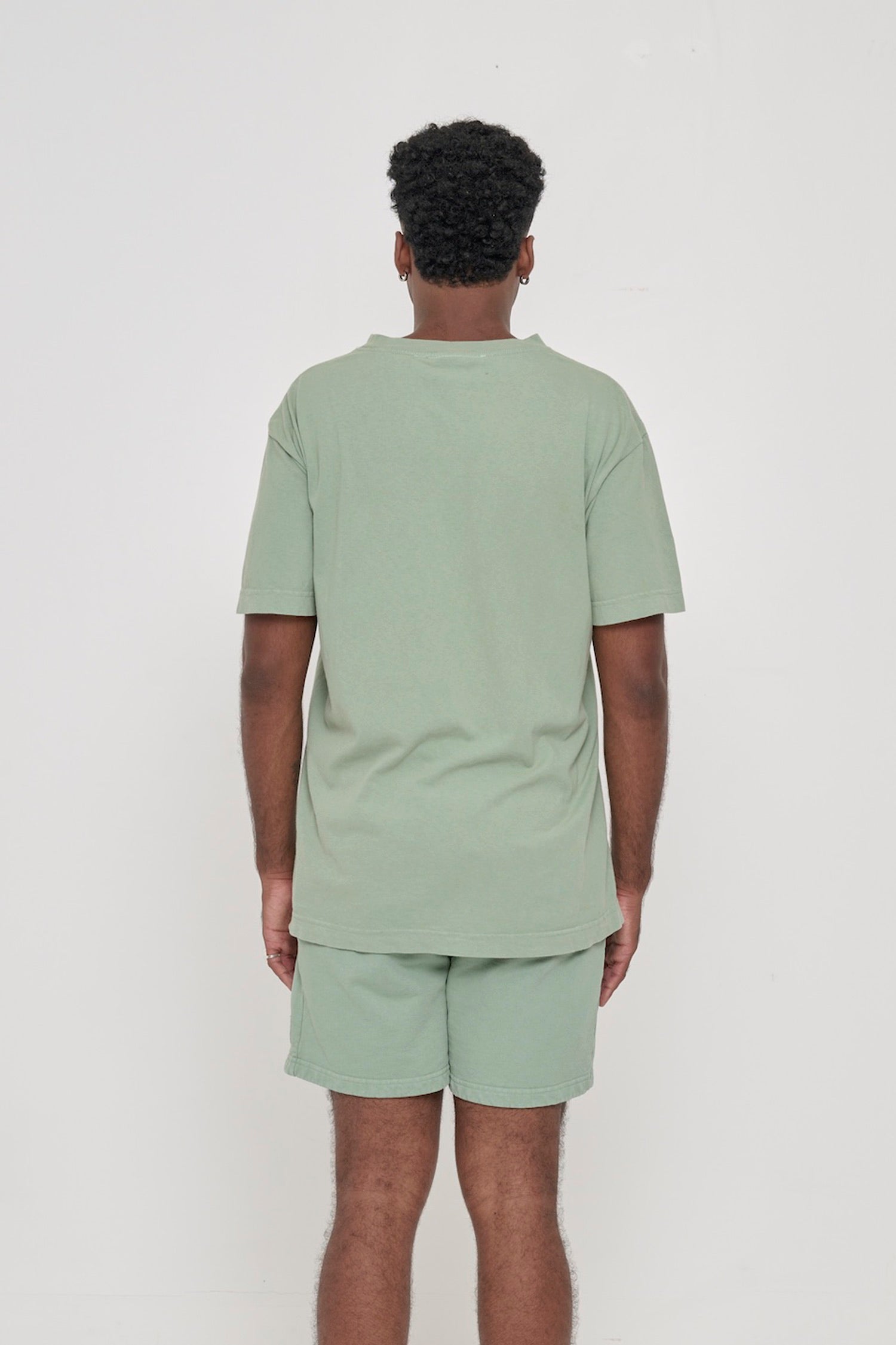 Back view of a man wearing the Short Sleeve Trash Tee in Wasabi, showing the relaxed slim body and wide sleeve.