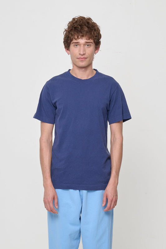 Front view of a non-binary model wearing the Short Sleeve Trash Tee in Washed Navy, showcasing its relaxed fit and navy blue color of Washed Navy.