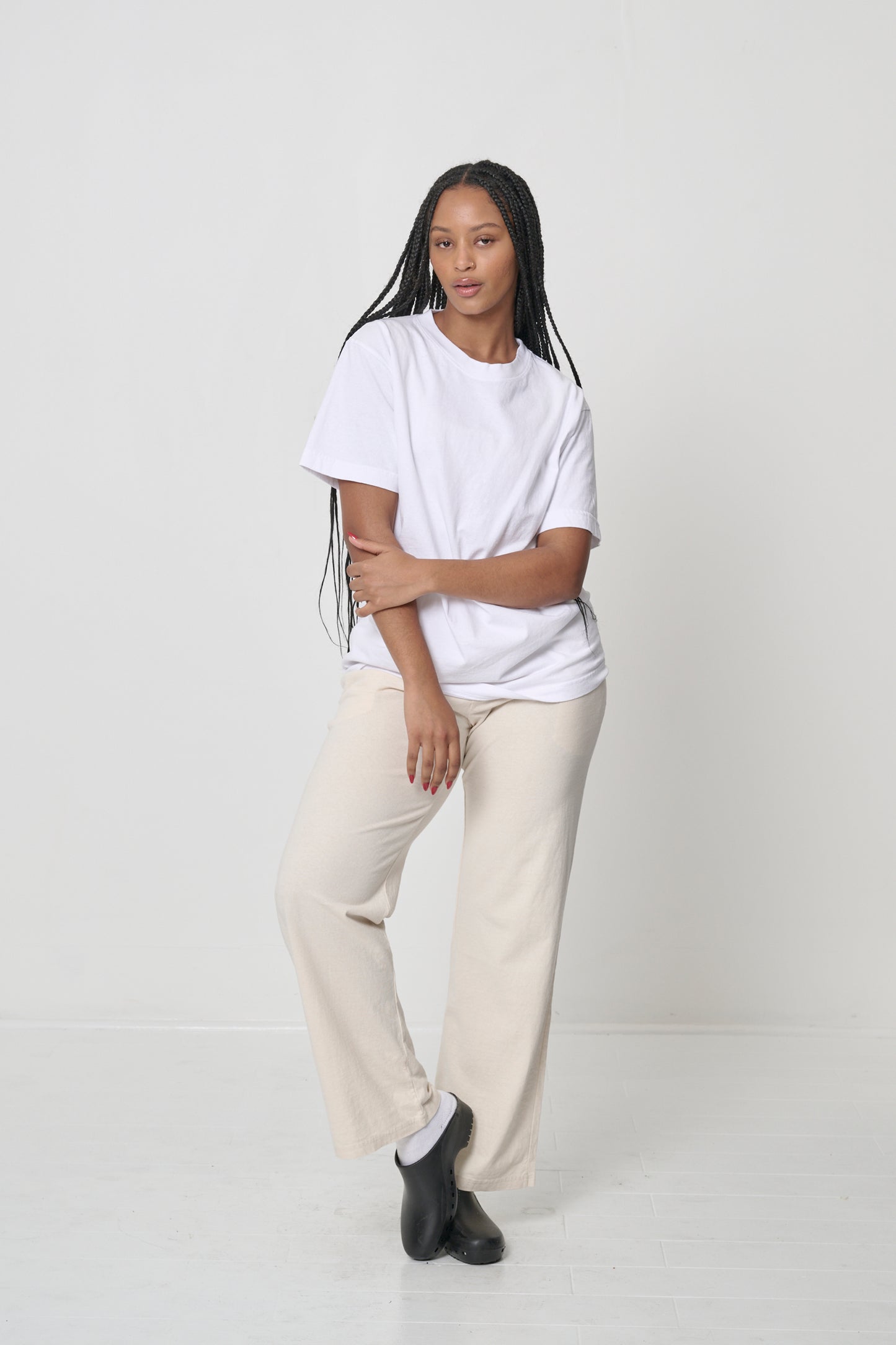 Front view of a woman wearing the Short Sleeve Trash Tee in White with a comfortable fit over a pair of Apartment Pants.