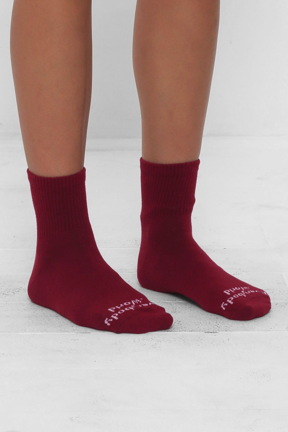 Angled view of Garnet Spring Socks, branded 'Everybody.World' in white, ankle-high, shown on lower legs.