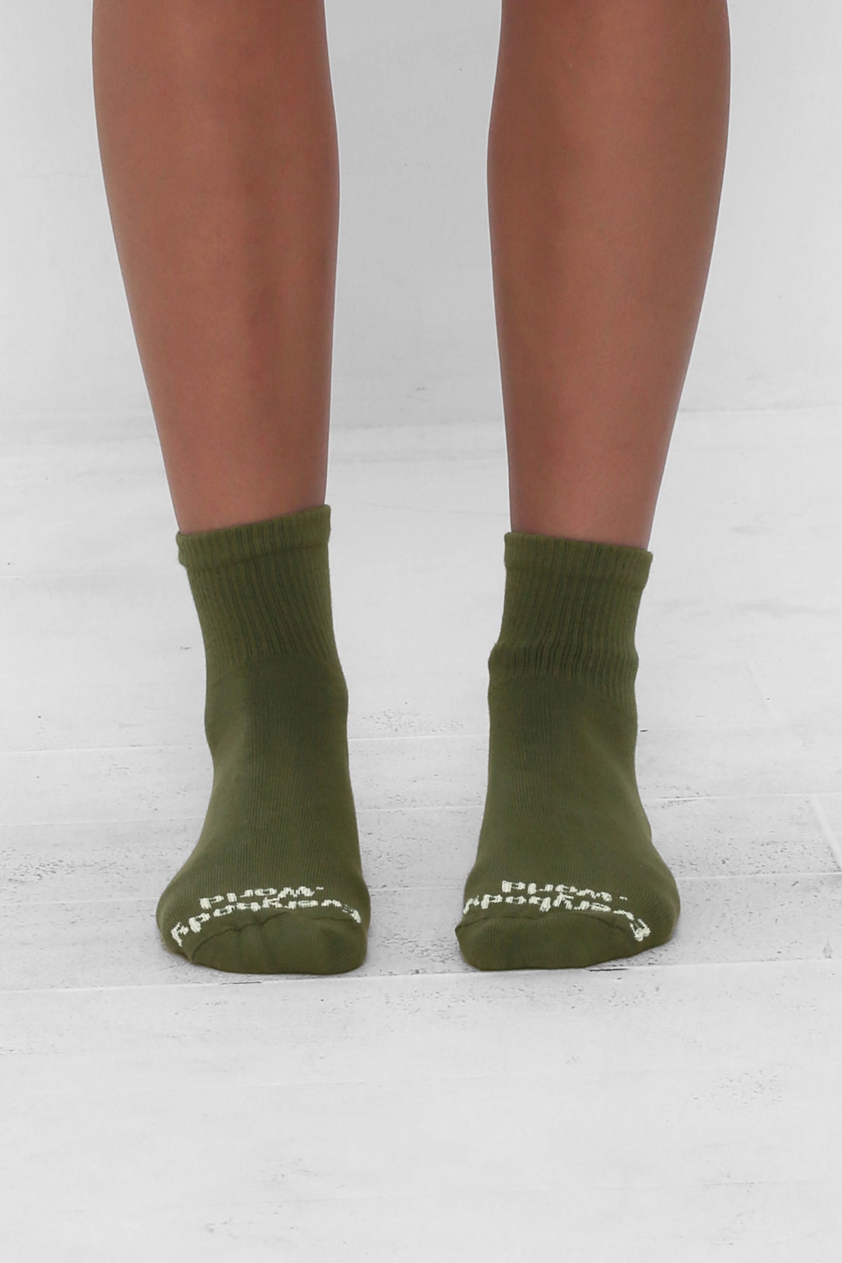 Angled view of Olive Spring Socks, branded 'Everybody.World' in white, ankle-high, shown on lower legs.