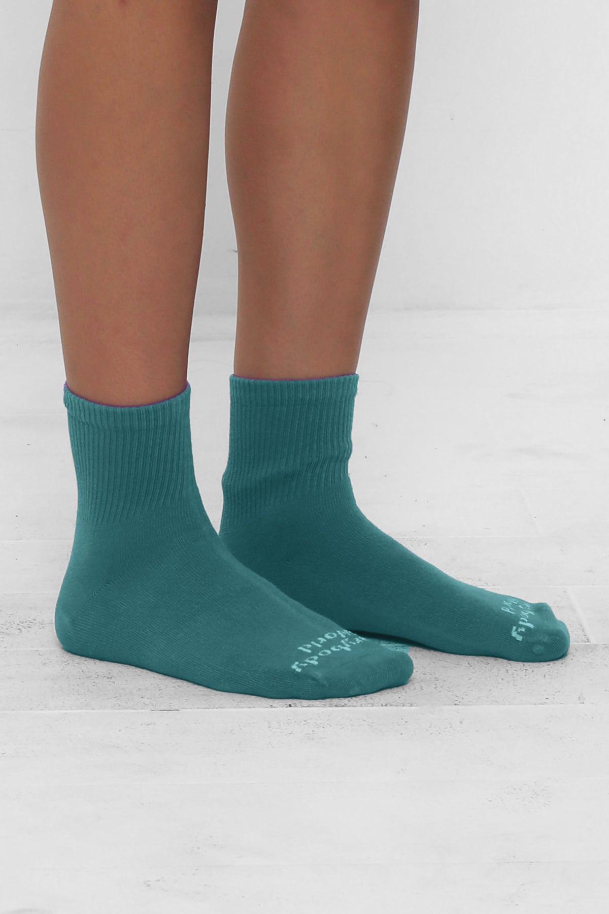 Angled view of Oyster Spring Socks, branded 'Everybody.World' in white, ankle-high, shown on lower legs.
