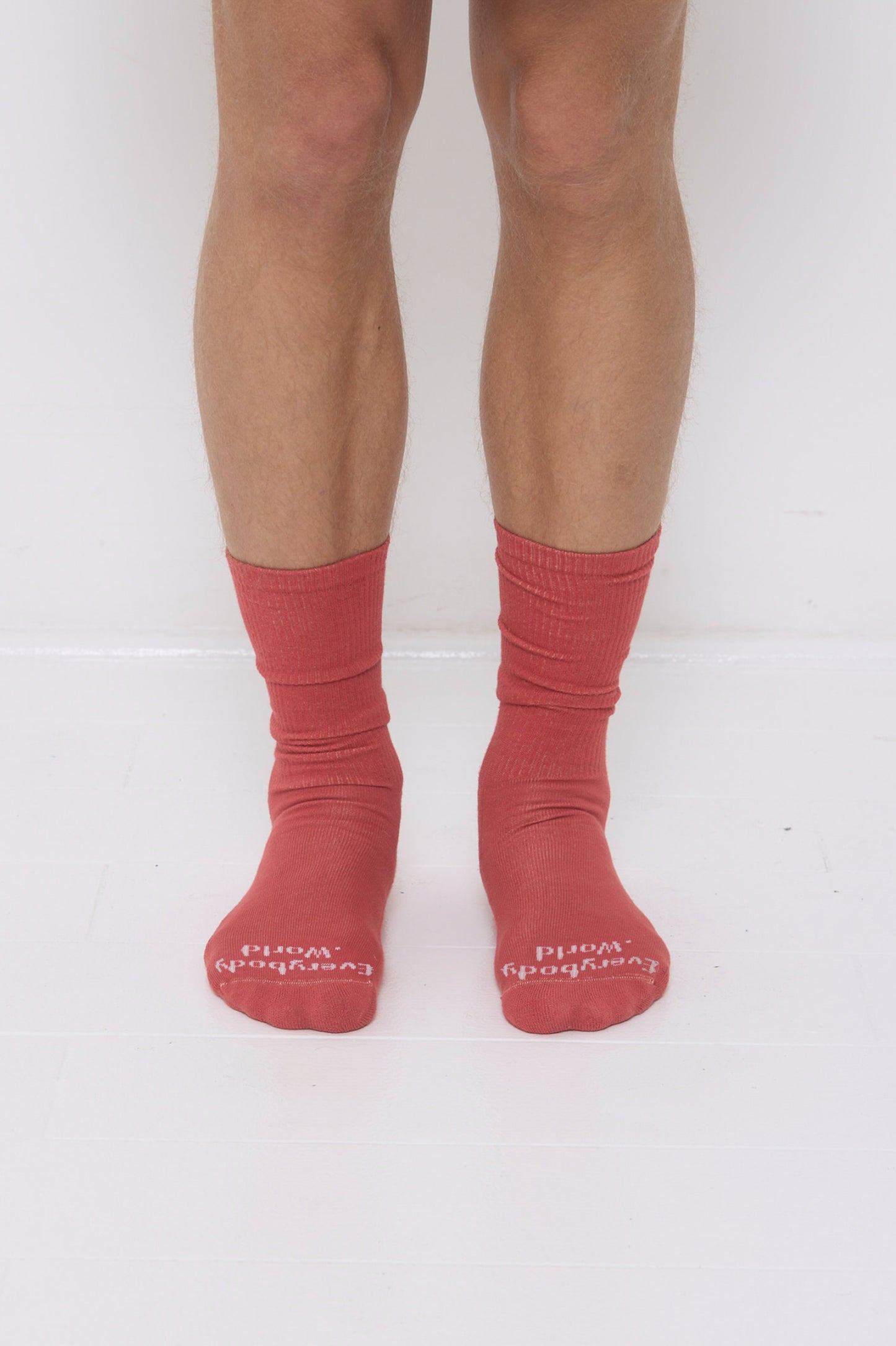 Cedar orange-red Squishy Socks, branded 'Everybody.World' at the toe, are calf-high, shown on a person's lower legs.