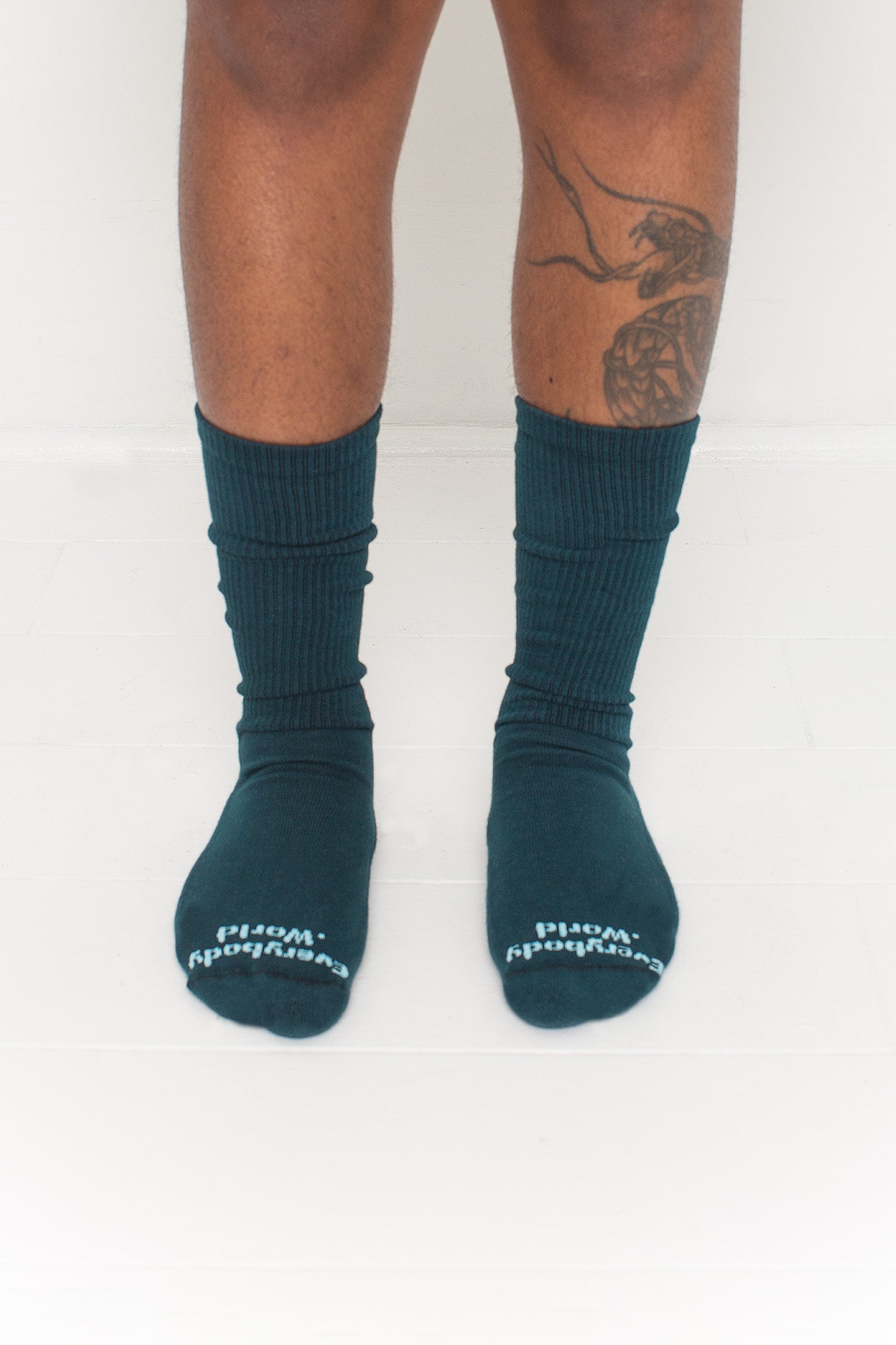 Juniper Squishy Socks, branded 'Everybody.World' in white at the toe, shown on a person's lower legs.