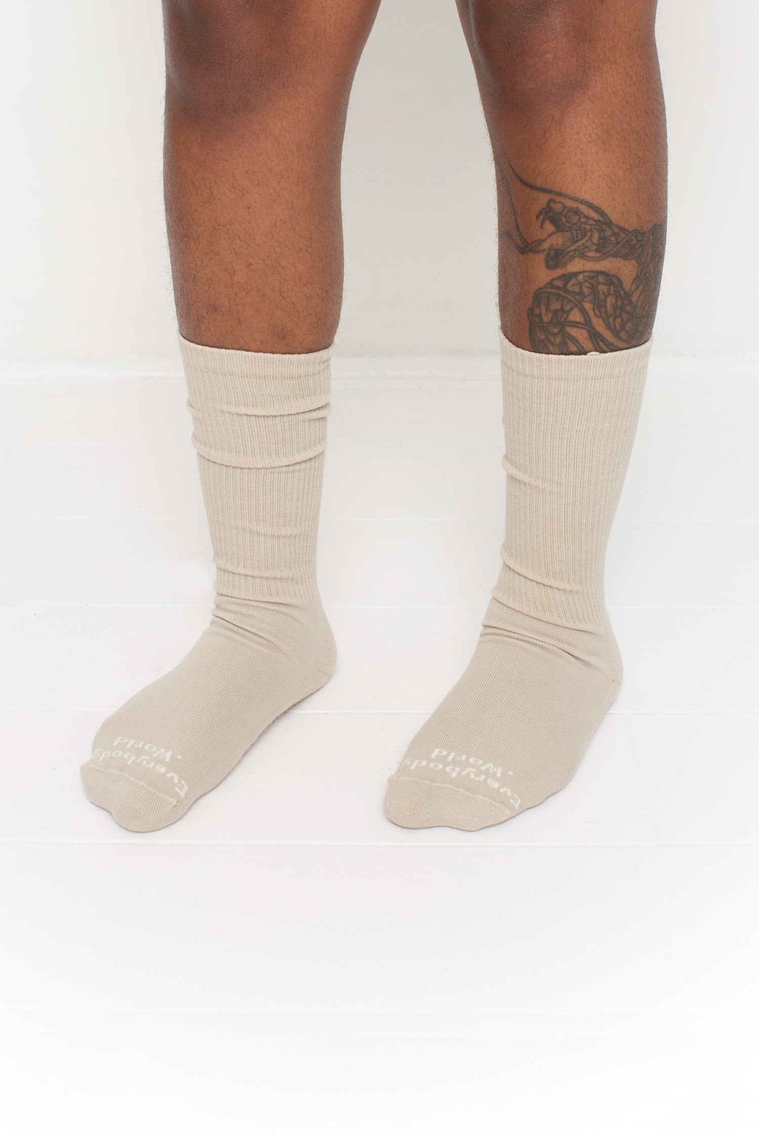 Oat Squishy Socks, branded 'Everybody.World' in white at the toe, shown on a person's lower legs.