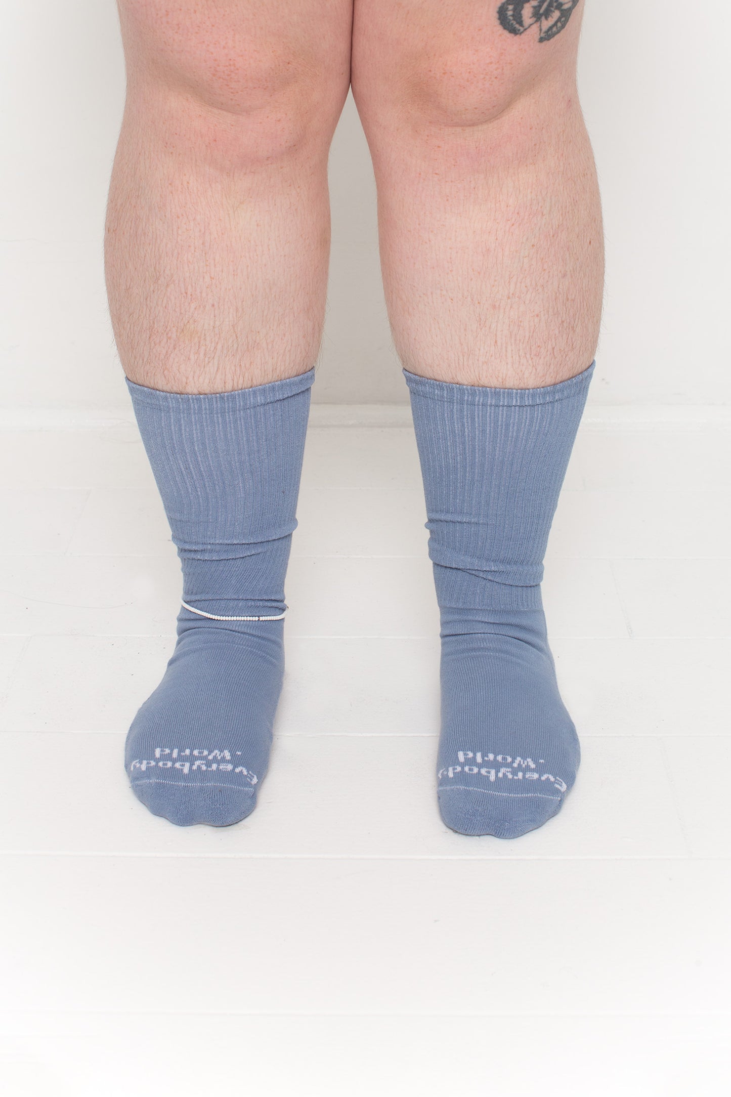 Periwinkle Squishy Socks, branded 'Everybody.World' in white at the toe, shown on a person's lower legs.