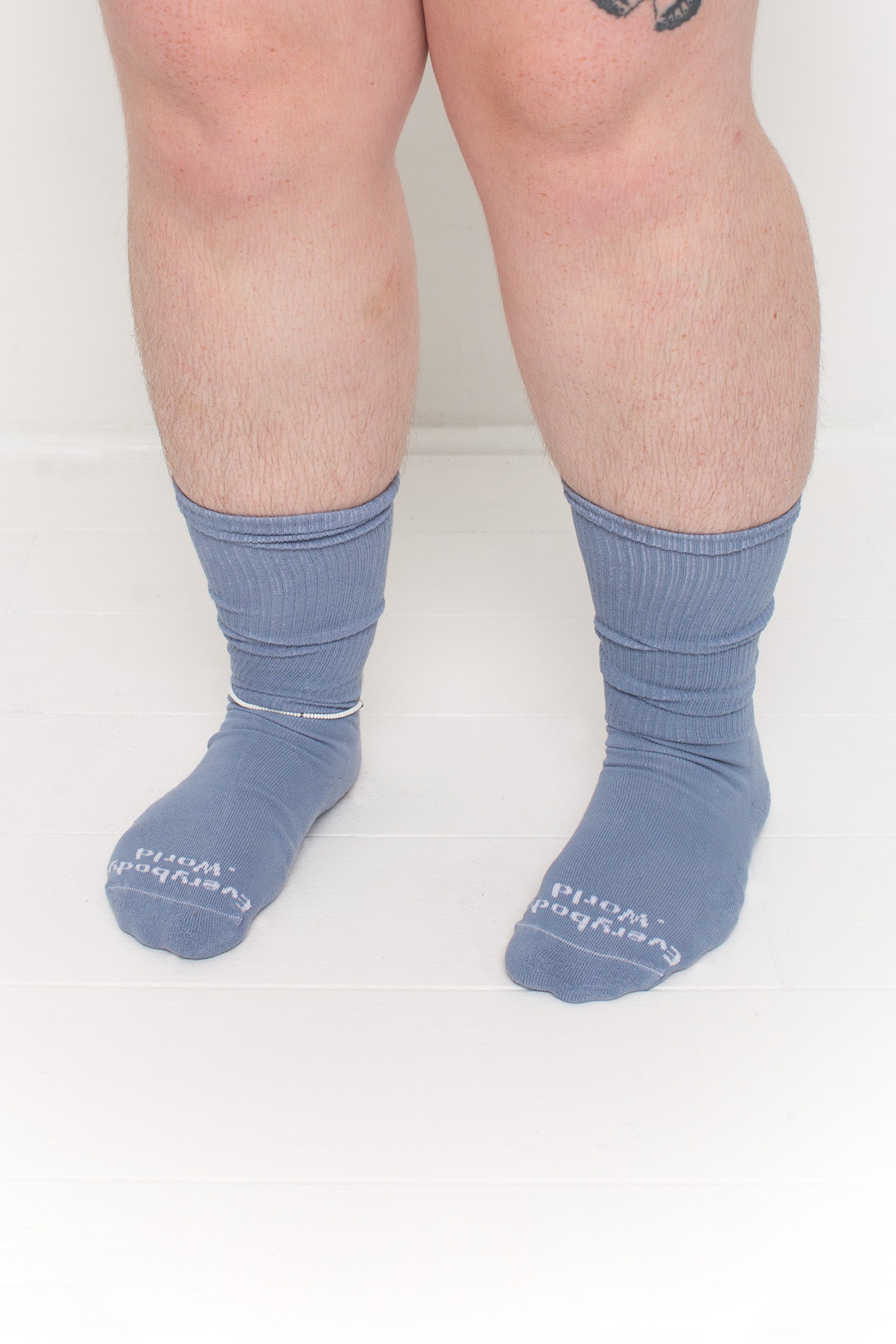 Periwinkle Squishy Socks, branded 'Everybody.World' in white at the toe, shown on a person's lower legs.
