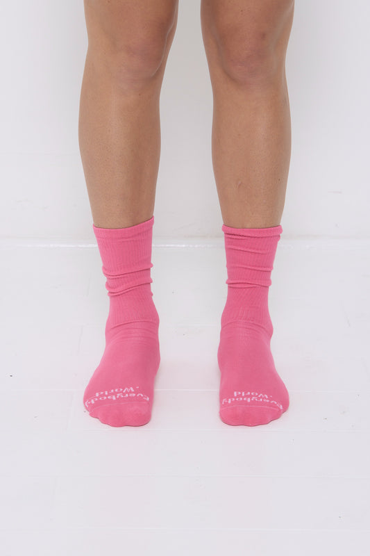 Popular bright pink Squishy Socks, branded 'Everybody.World' at the toe, are calf-high, shown on a person's lower legs.