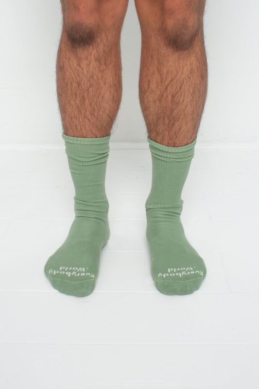 Wasabi Squishy Socks, branded 'Everybody.World' in white at the toe, shown on a person's lower legs.