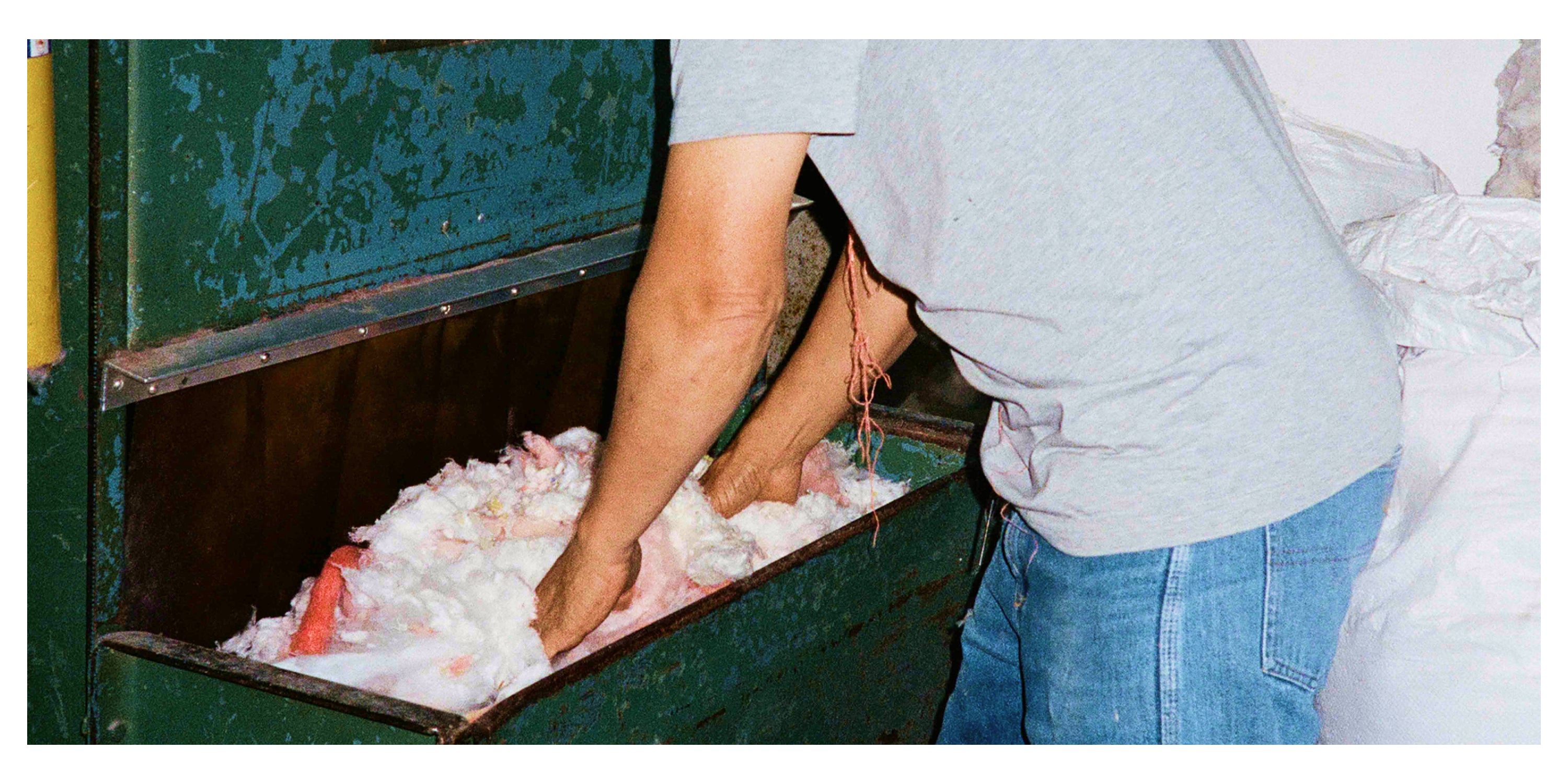 A worker’s hands sorting through colorful cotton fibers in an industrial setting, showcasing textile recycling processes.