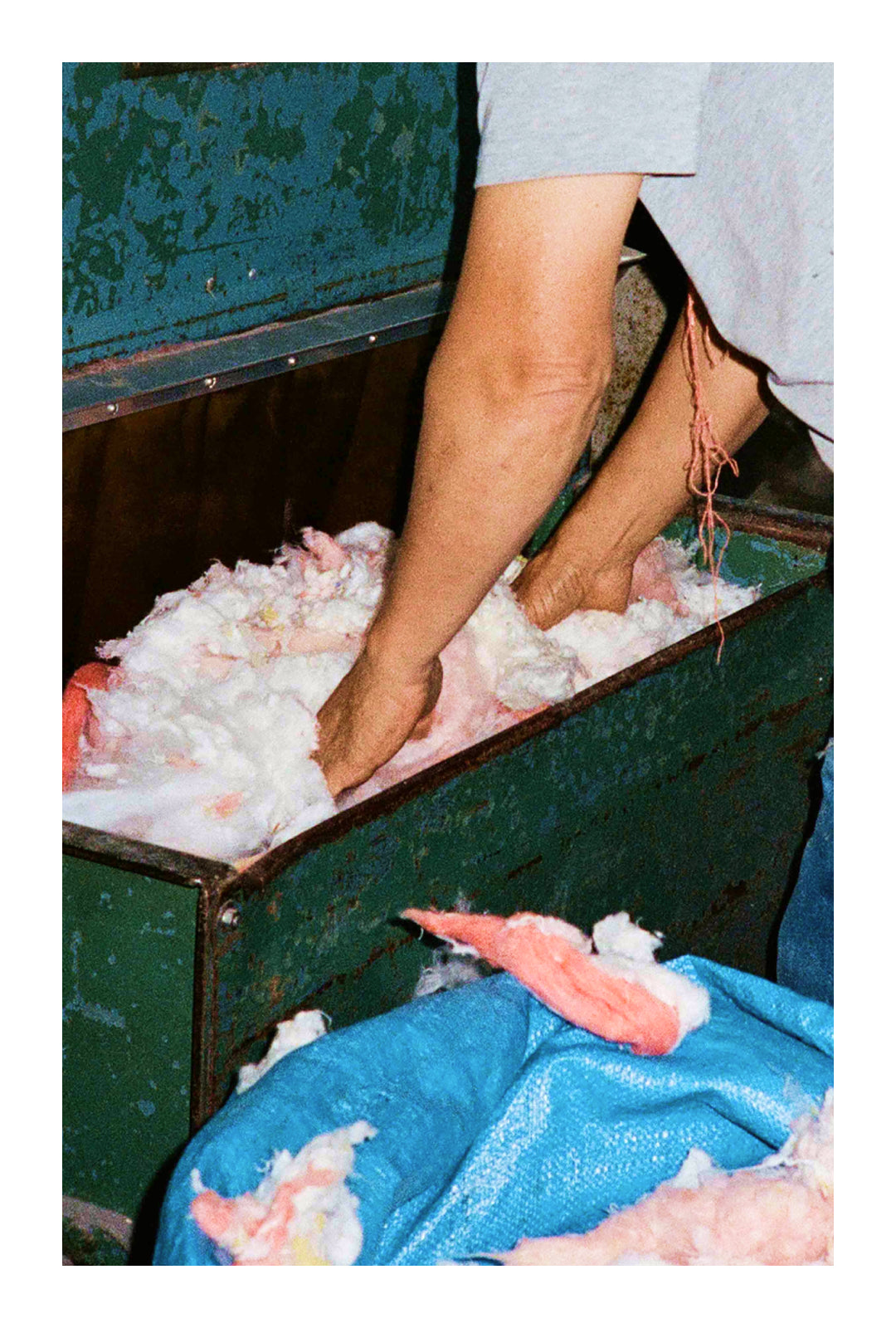 A worker’s hands sorting through colorful cotton fibers in an industrial setting, showcasing textile recycling processes.