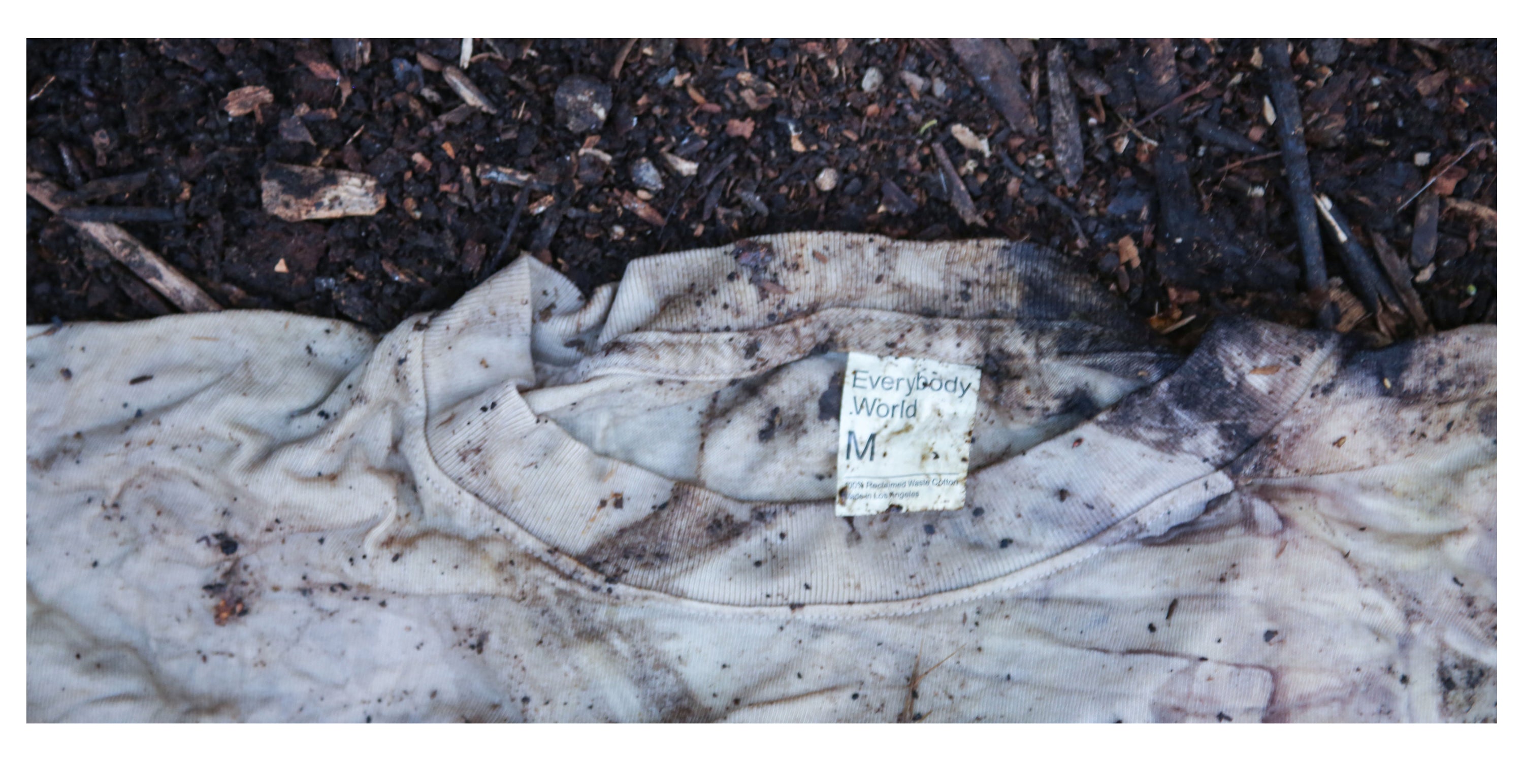 Close up of Boxier Trash Tee laying in the dirt, in the process of becoming compost.