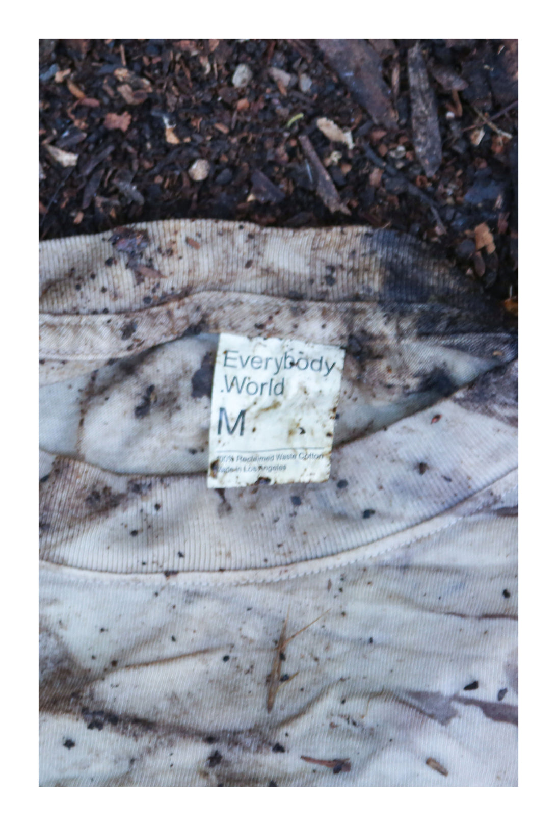 Close up of Boxier Trash Tee laying in the dirt, in the process of becoming compost.