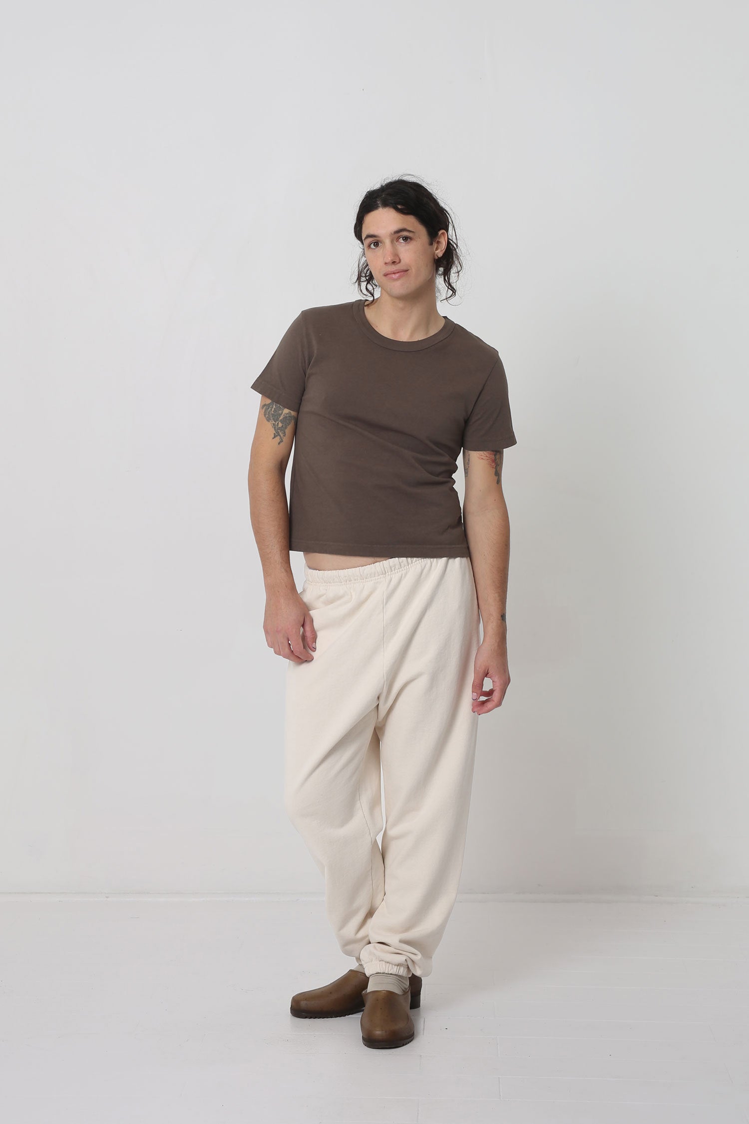 Person leaning slightly; cropped hem raised, exposing an inch of their waist.