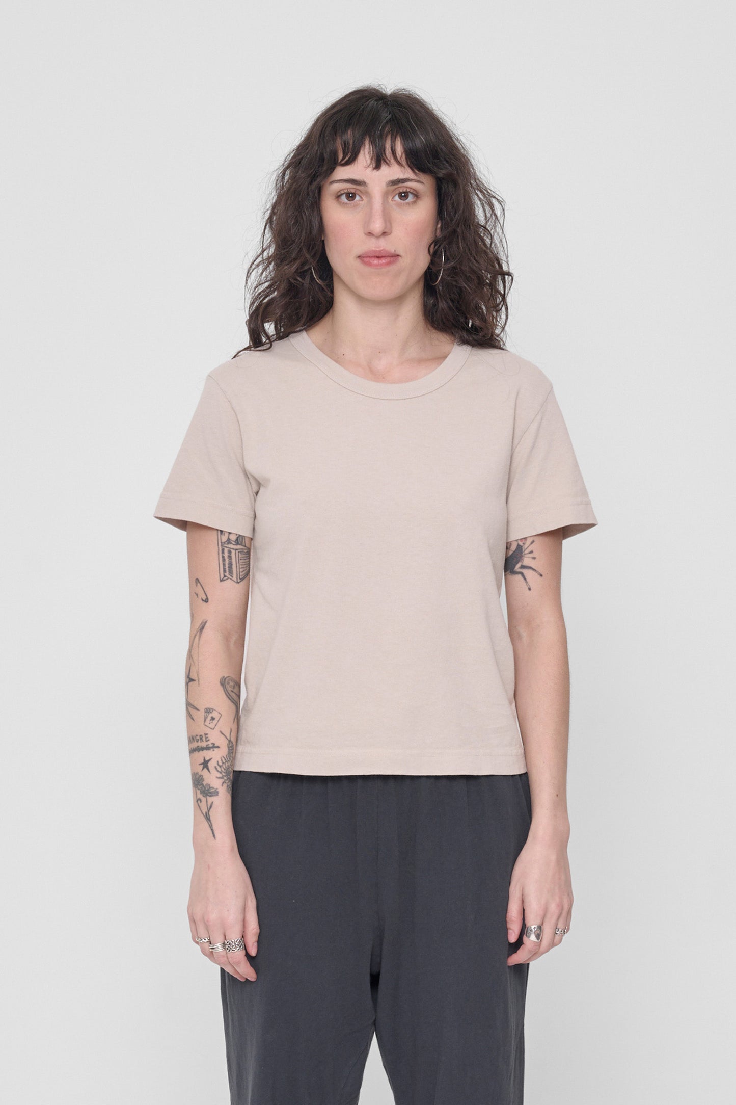 A 5'6" woman in a size S Oat Tailored Trash Tee. Hem ends at her upper hip. 