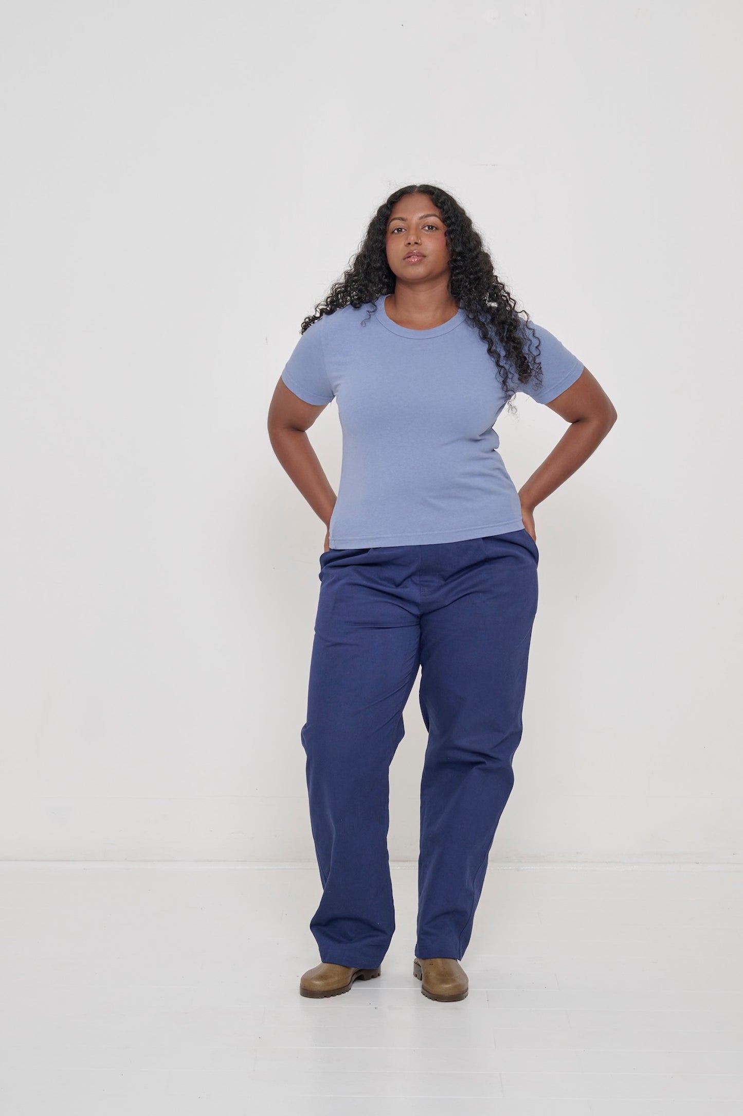 Woman in Periwinkle Tailored Trash Tee and Washed Navy Cotton Twill Life Uniform Pants, hands on hips.