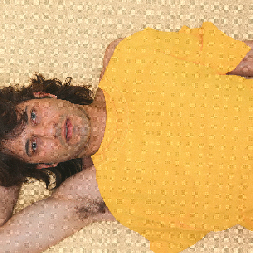 Man laying on the ground with a Trash Tee in Everybody Yellow draped over his torso.