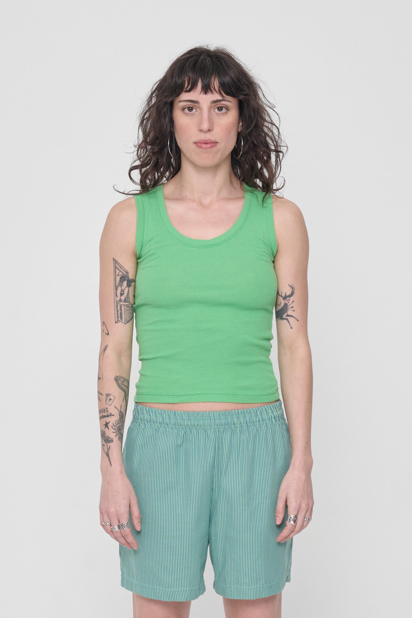 A 5'6" woman wearing a size XS The Tank in Nice Grass. Hem hits her just below her navel.