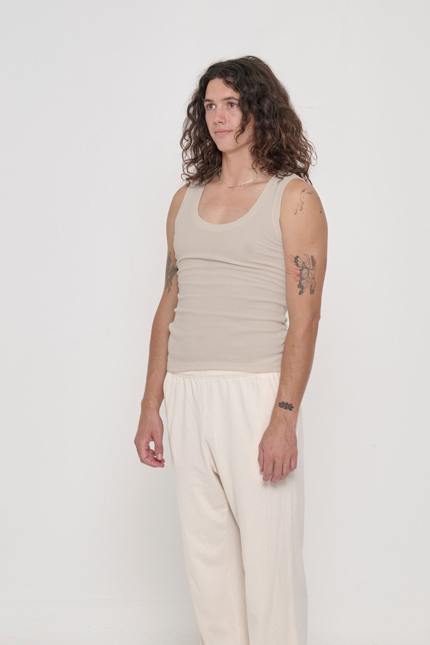 A person facing 45-degrees, wearing The Tank in Oat, showcasing side seams and fitted silhouette.