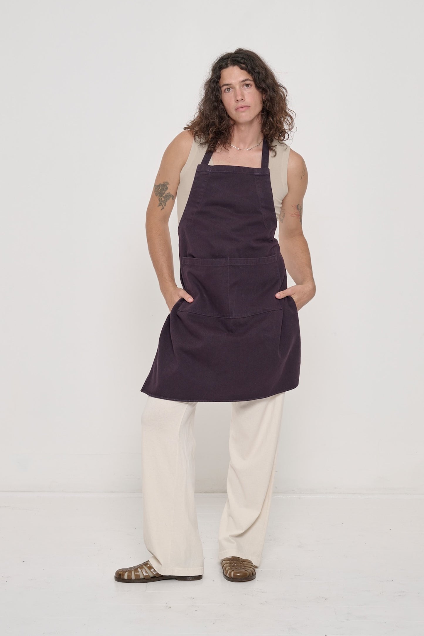 A person wearing The Tank in Oat with hands in the pockets of their Mulberry Adjustable Apron.