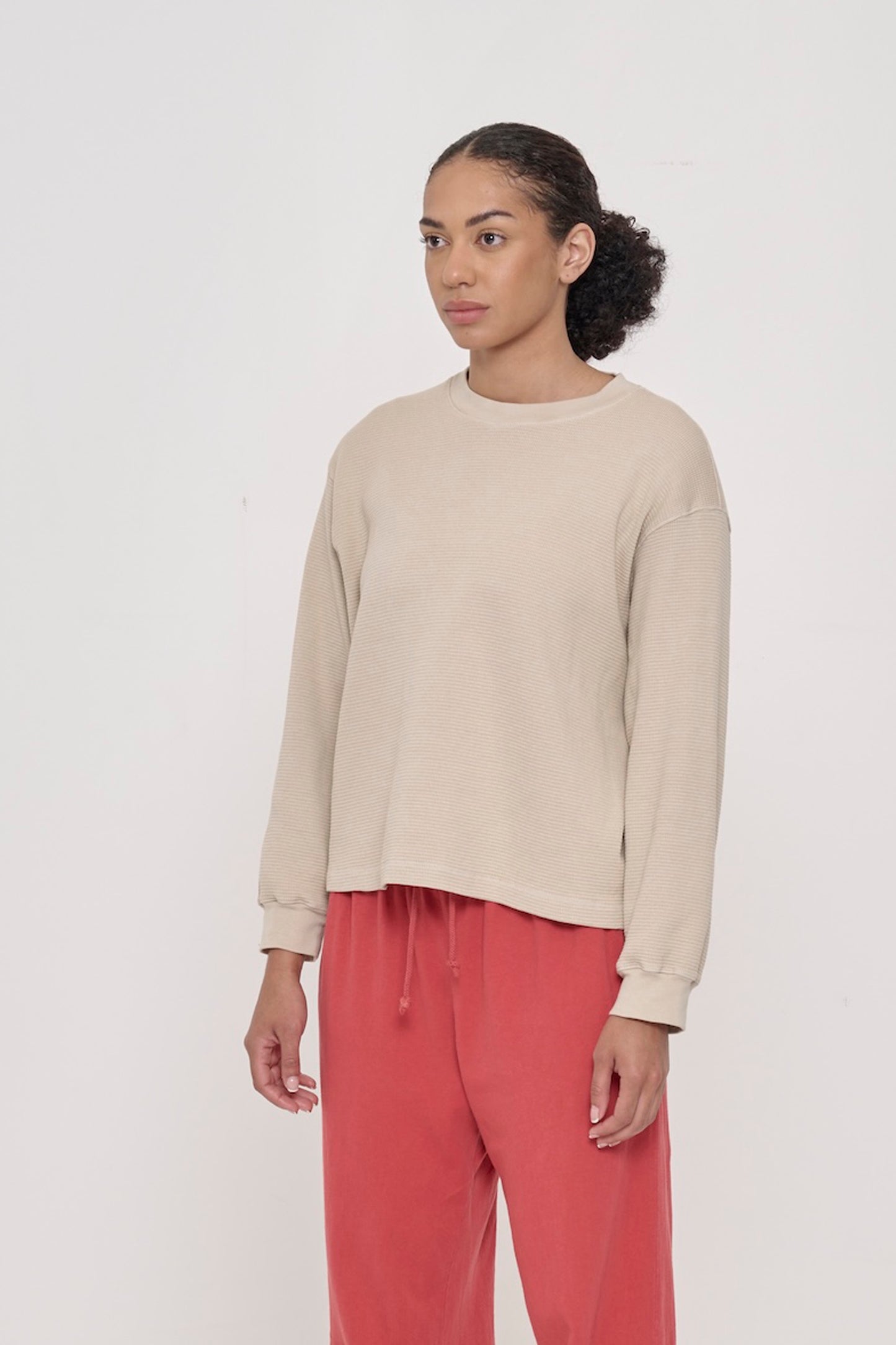 A person facing 45-degrees from front, in Oat Thermal Long Sleeve Boxier Trash Tee. Shows relaxed sleeves and rib cuff.