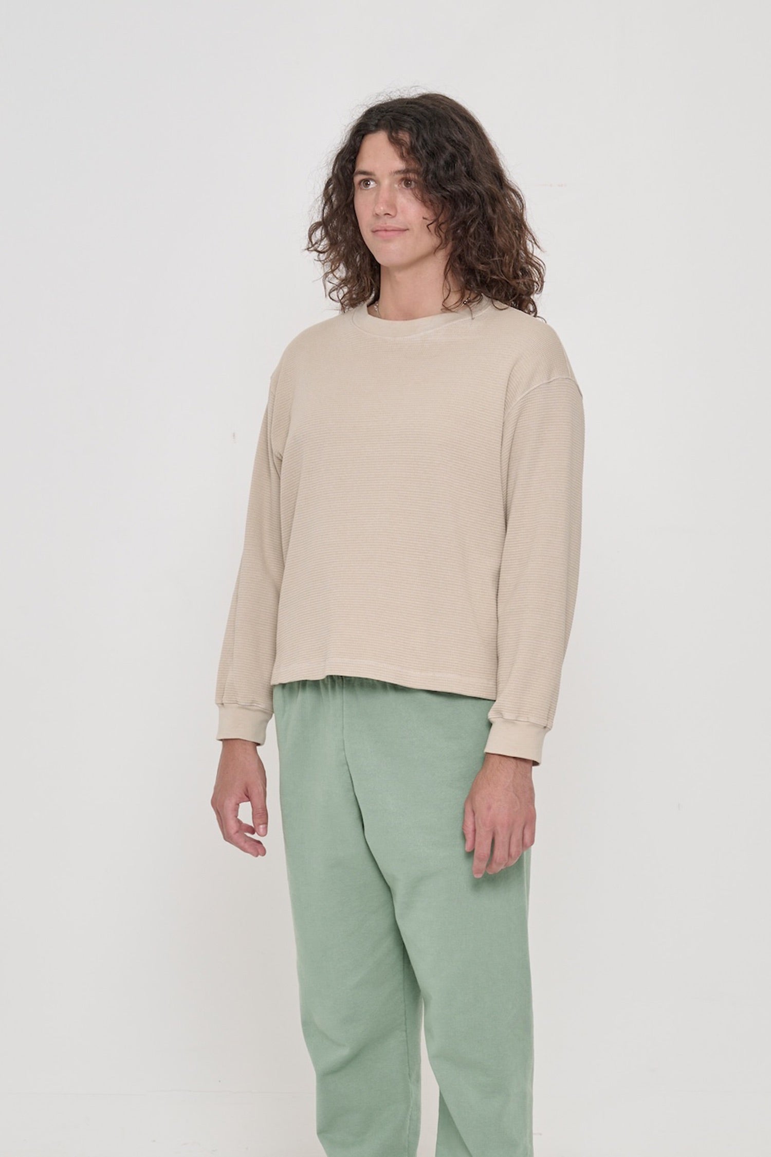 A person facing 45-degrees from front, in Oat Thermal Long Sleeve Boxier Trash Tee. Shows relaxed sleeves and rib cuff.