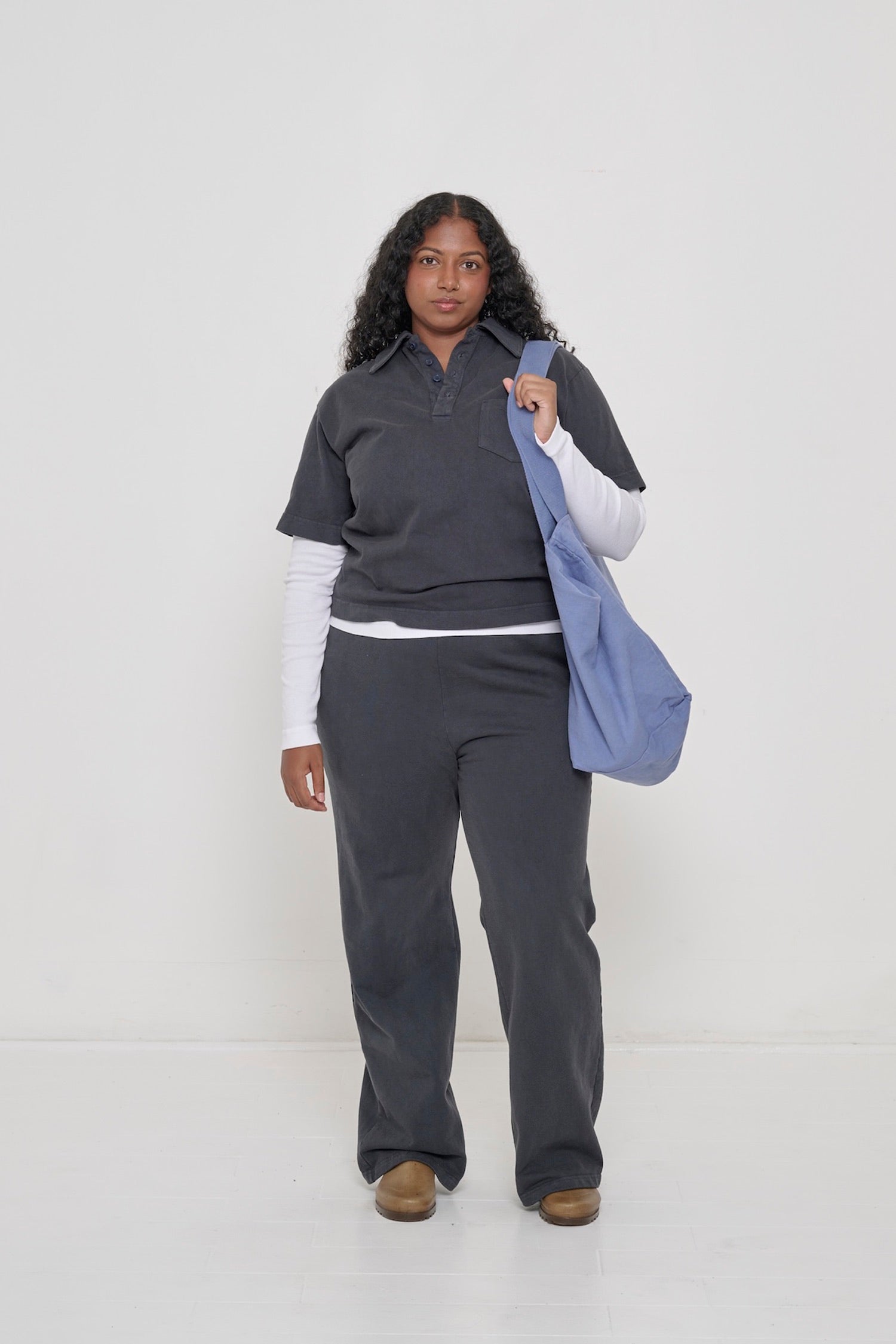 A woman in a Slate Trash Polo layered over a White Rib Long Sleeve. A Big Tote on her shoulder.