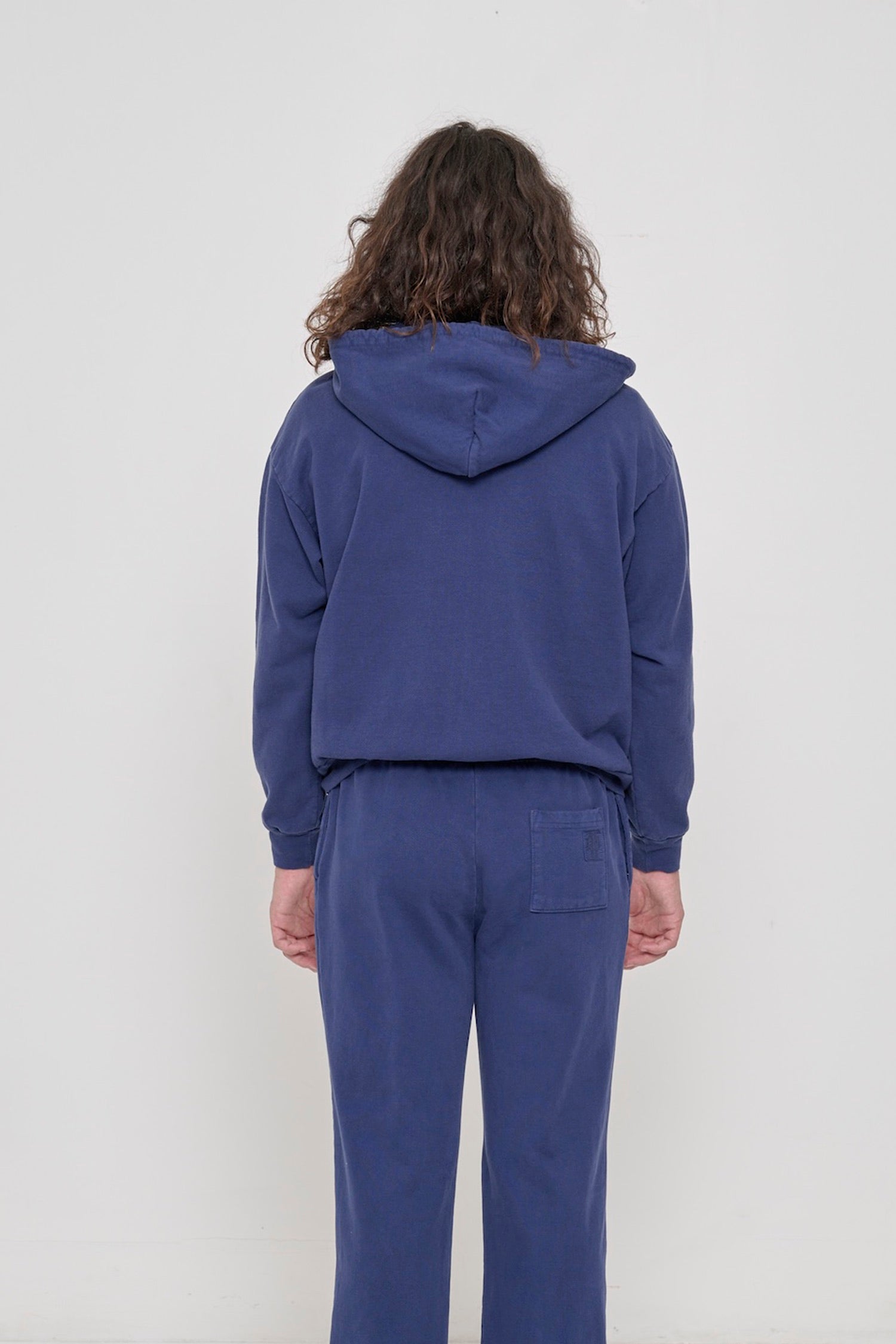 Back view: A person wearing a Washed Navy Zip Up Trash Hoodie, highlighting the hood.
