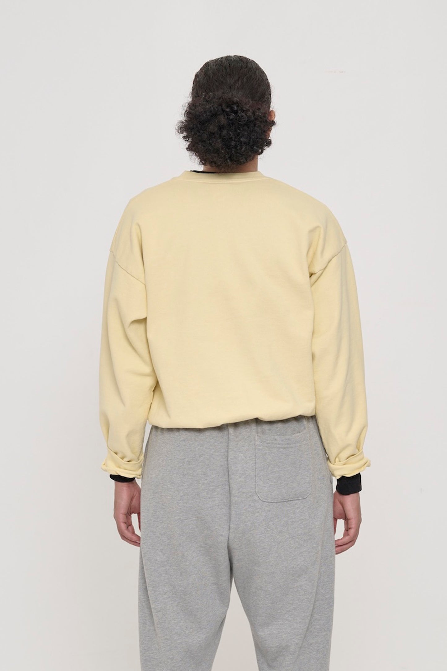 Back view on a person in French Butter Trash Crewneck, relaxed throughout until the rib hem and cuffs.