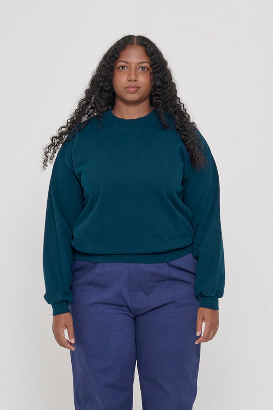Front view of a person wearing Juniper Trash Crewneck. Hem hits their upper hip.