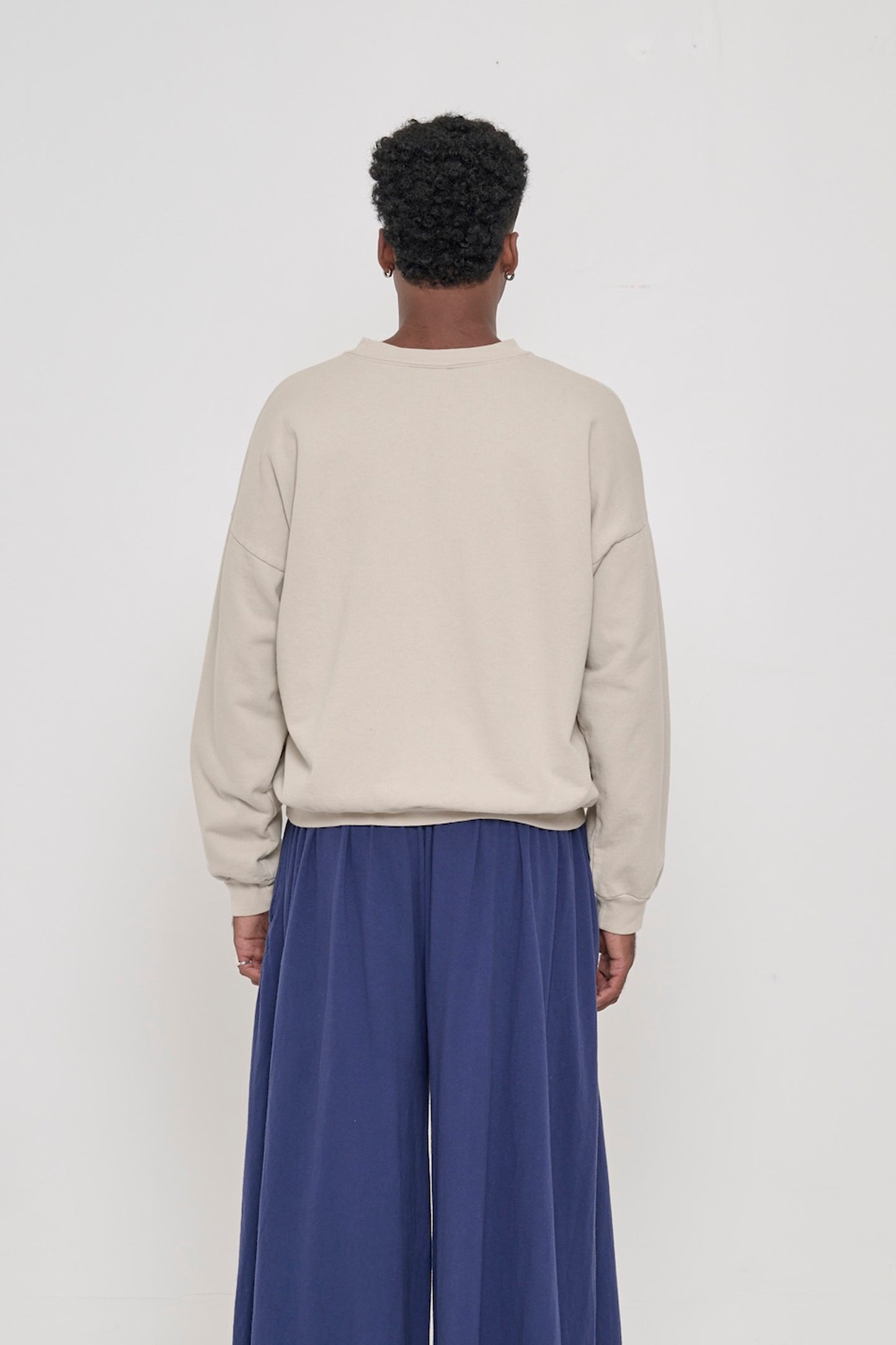Back view on a person in Oat Trash Crewneck, relaxed throughout until the rib hem and cuffs.