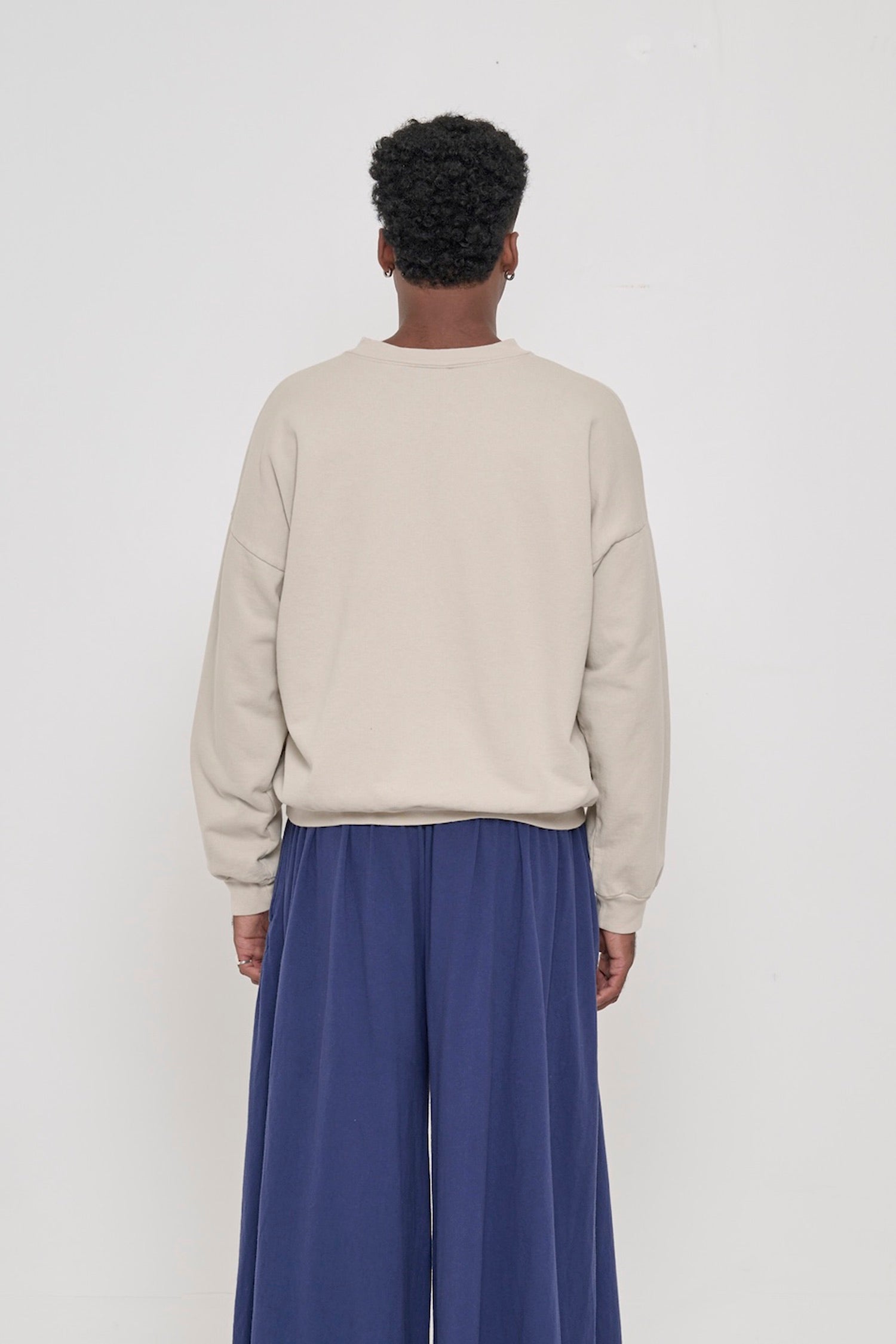 Back view on a person in Oat Trash Crewneck, relaxed throughout until the rib hem and cuffs.